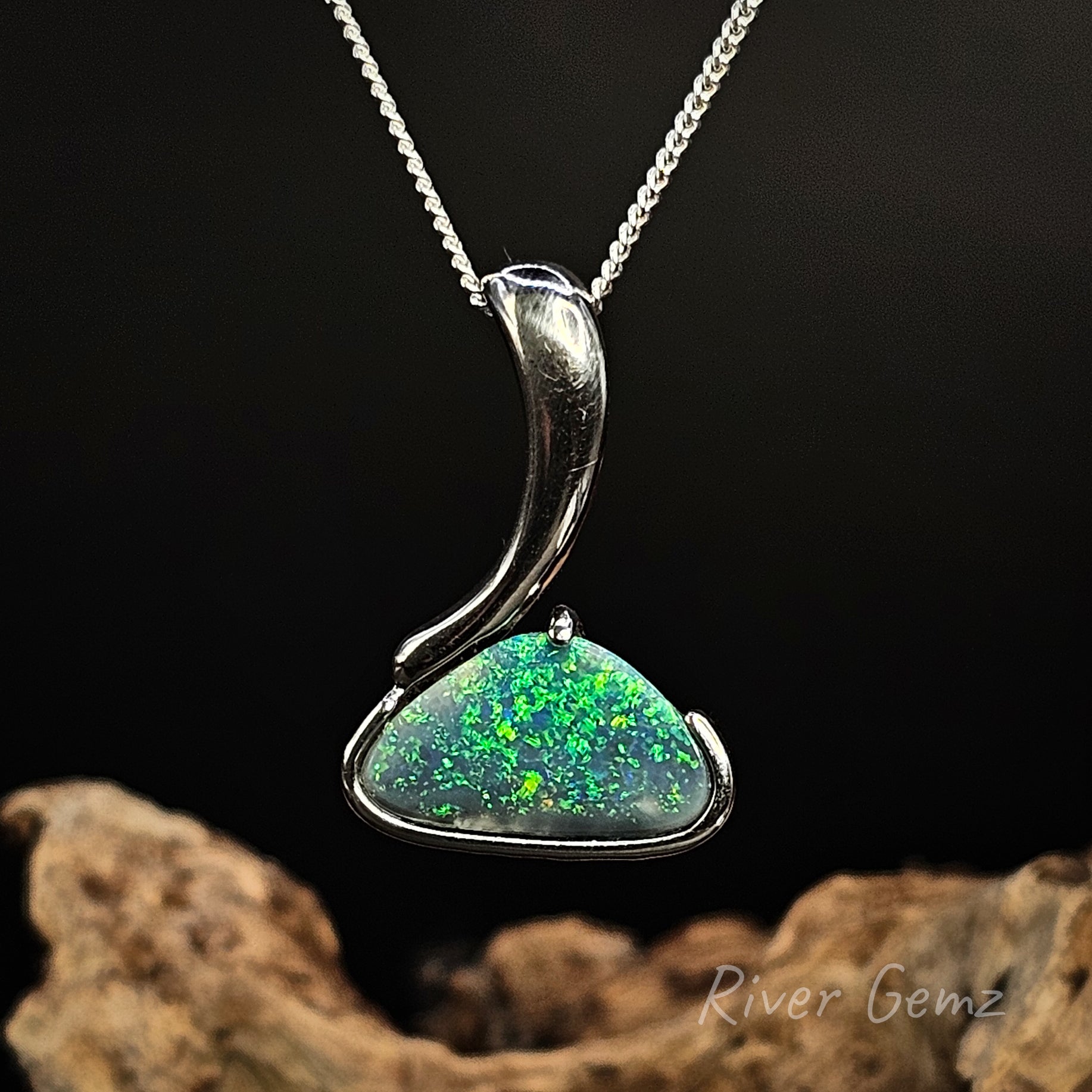 Black opal in sterling silver pendant on a chain with a dark background