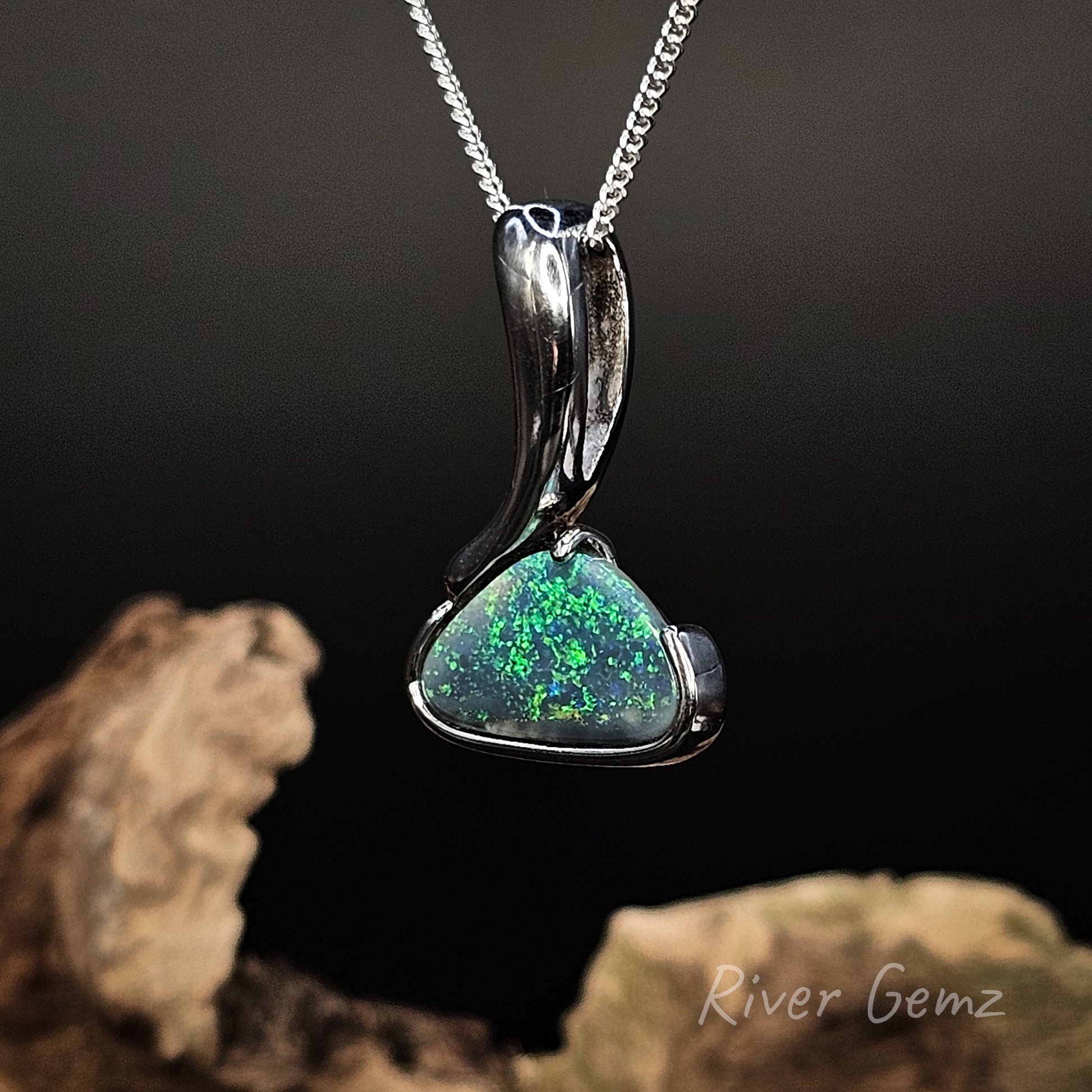 Opal pendant with a large hidden bail on a chain with a dark background