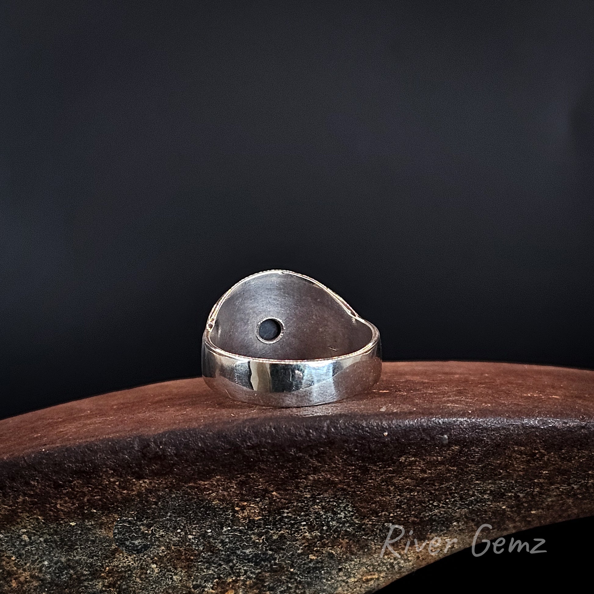 Rear view shows the silver backing behind the opal with a small hole left to reveal the dark base tone of the black opal.