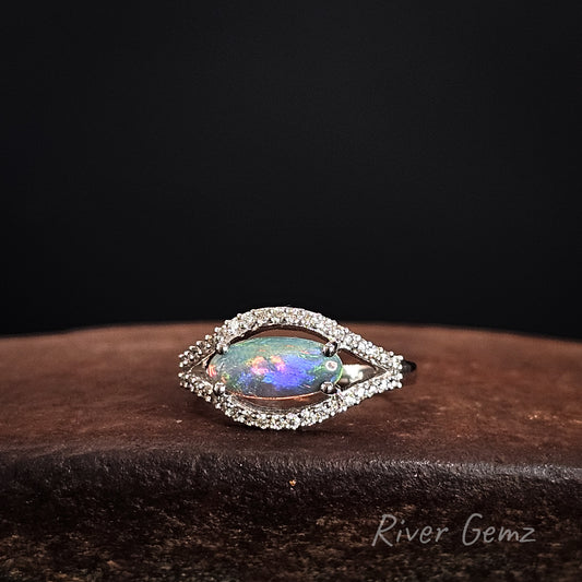 Opal ring with diamond accents on a dark background, branded 'River Gemz'.