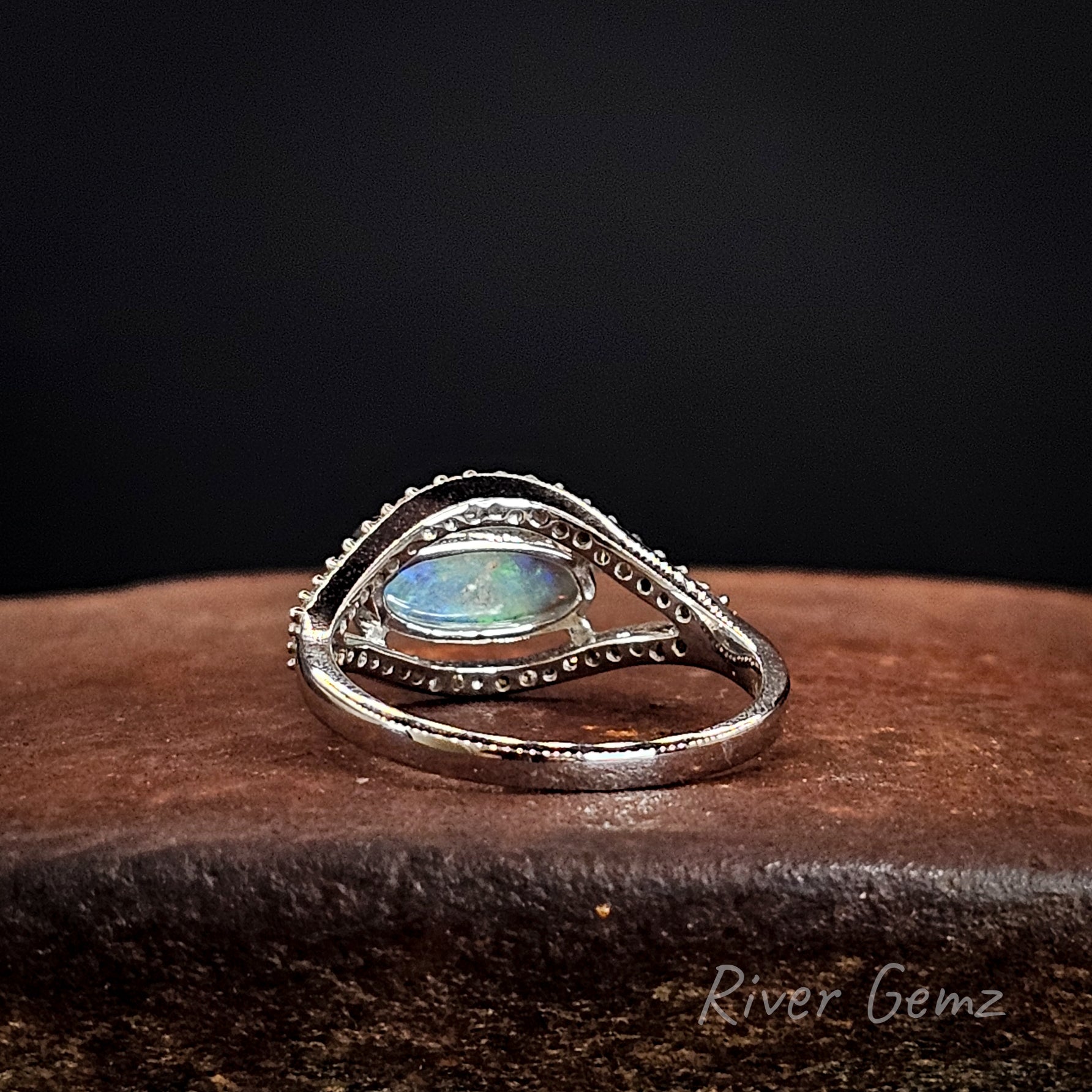 Back view of ring shows the light base tone of the included crystal opal on a dark background.