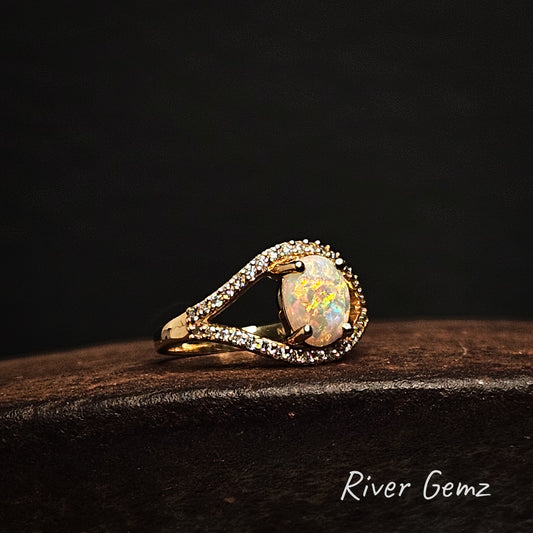 Opal ring with gold and diamond accents on a dark background, branded 'River Gemz'.