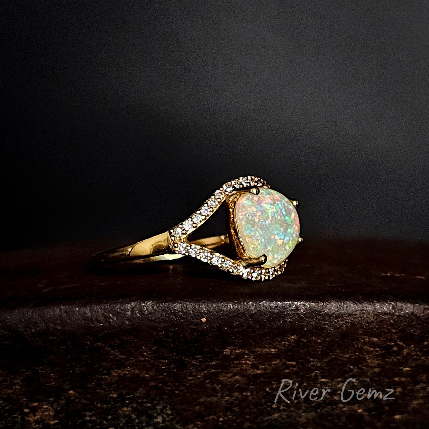 Opal ring with gold band on a dark background, featuring 'River Gemz' branding.