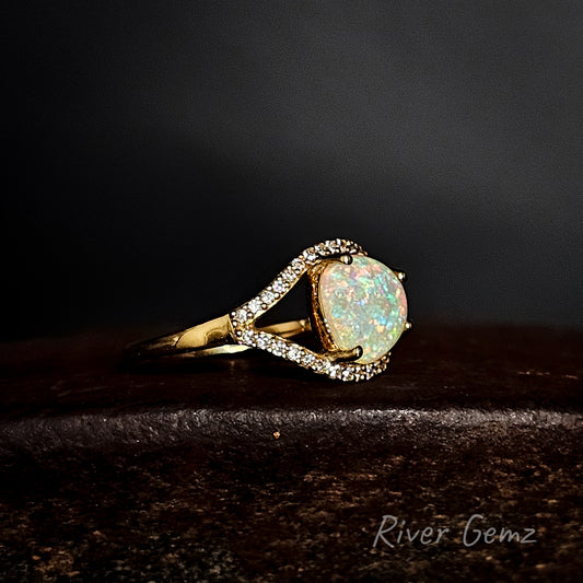 Opal ring with gold band on a dark background, featuring 'River Gemz' branding.