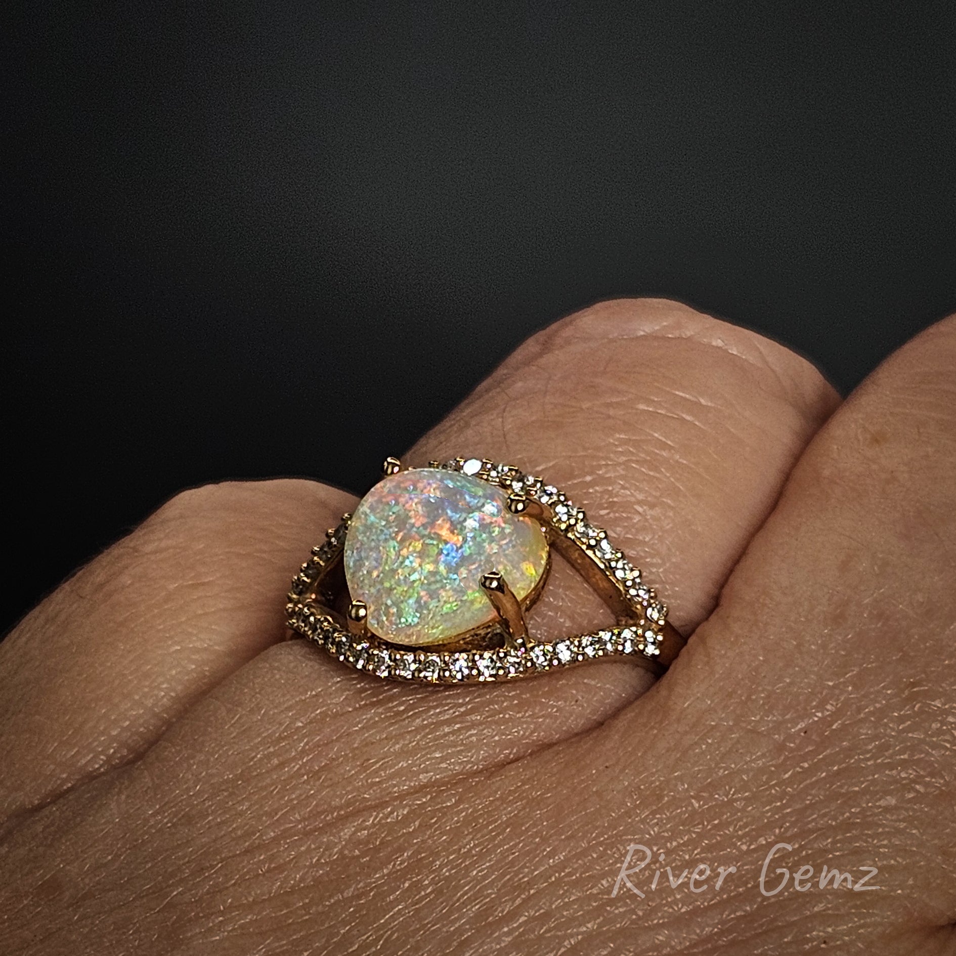 Ring with a large opal stone on a finger against a dark background