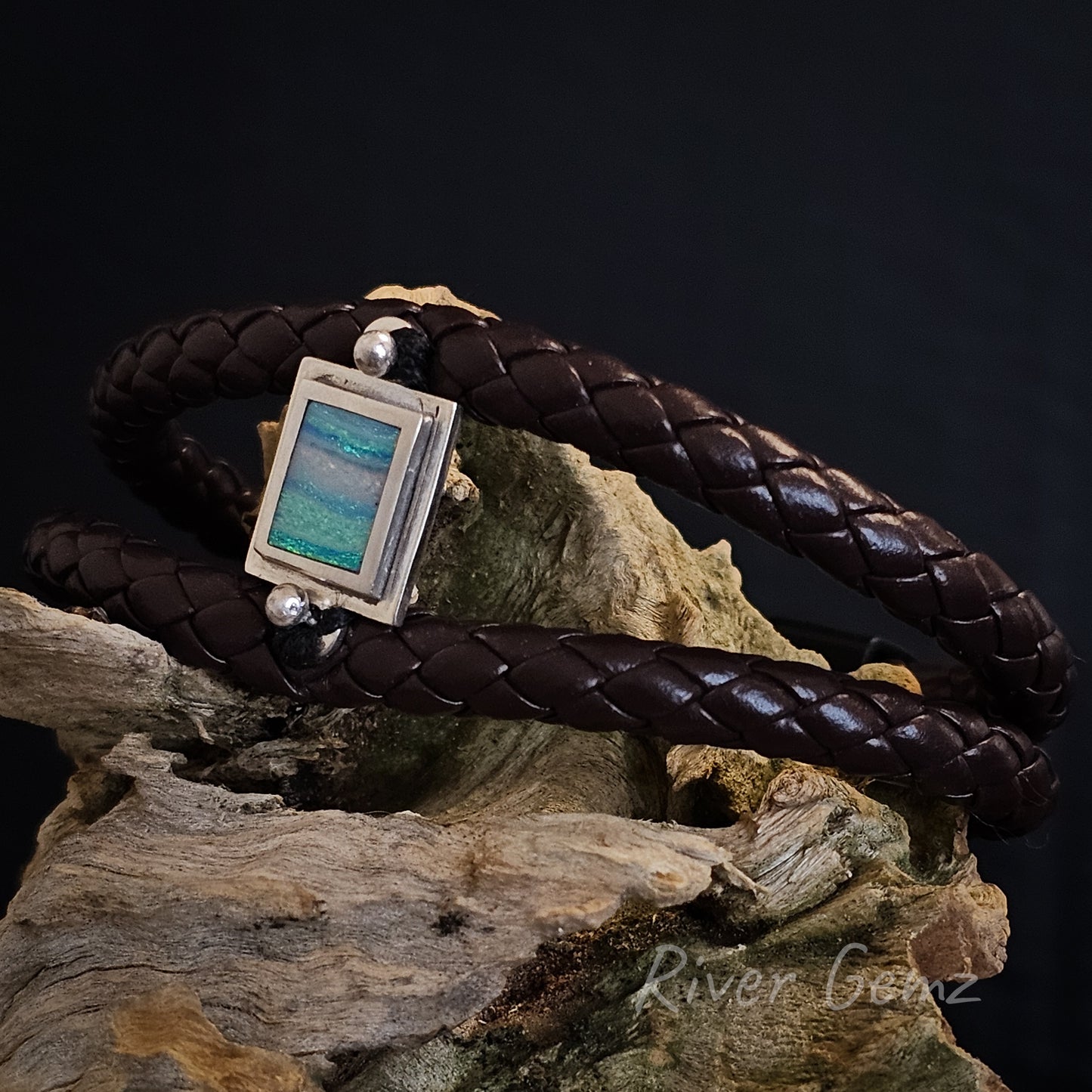 Dark brown leather bracelet with a pink, green and blue coloured light opal in a silver setting.