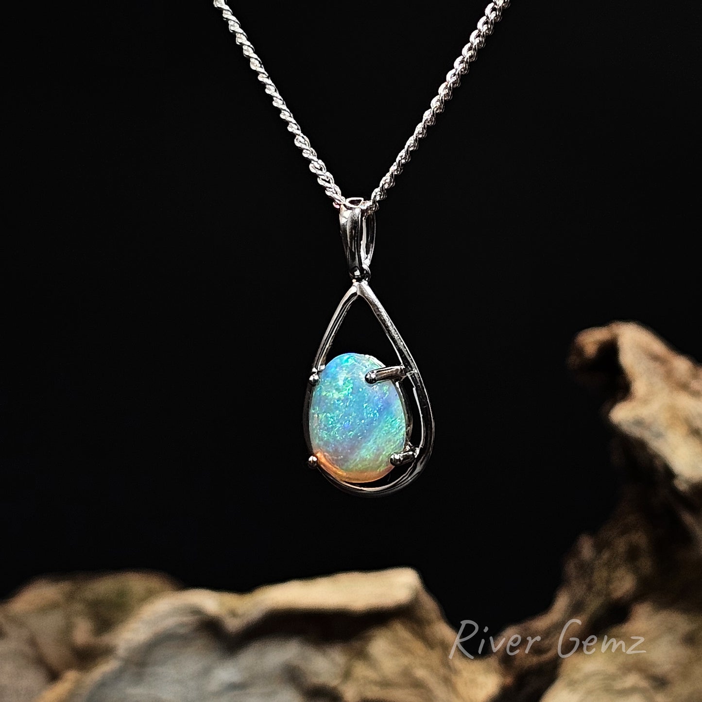 Teardrop shaped opal set in sterling silver necklace on a dark background with 'River Gemz' branding.
