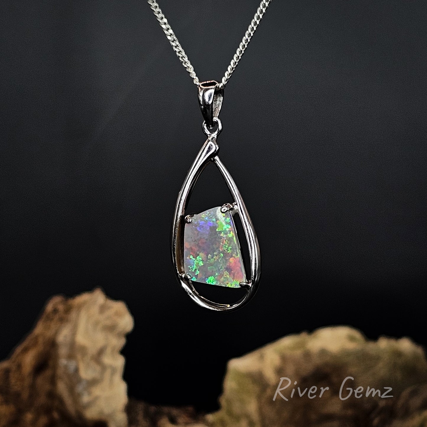 4-sided multi-coloured opal set in tear drop shaped silver pendant.