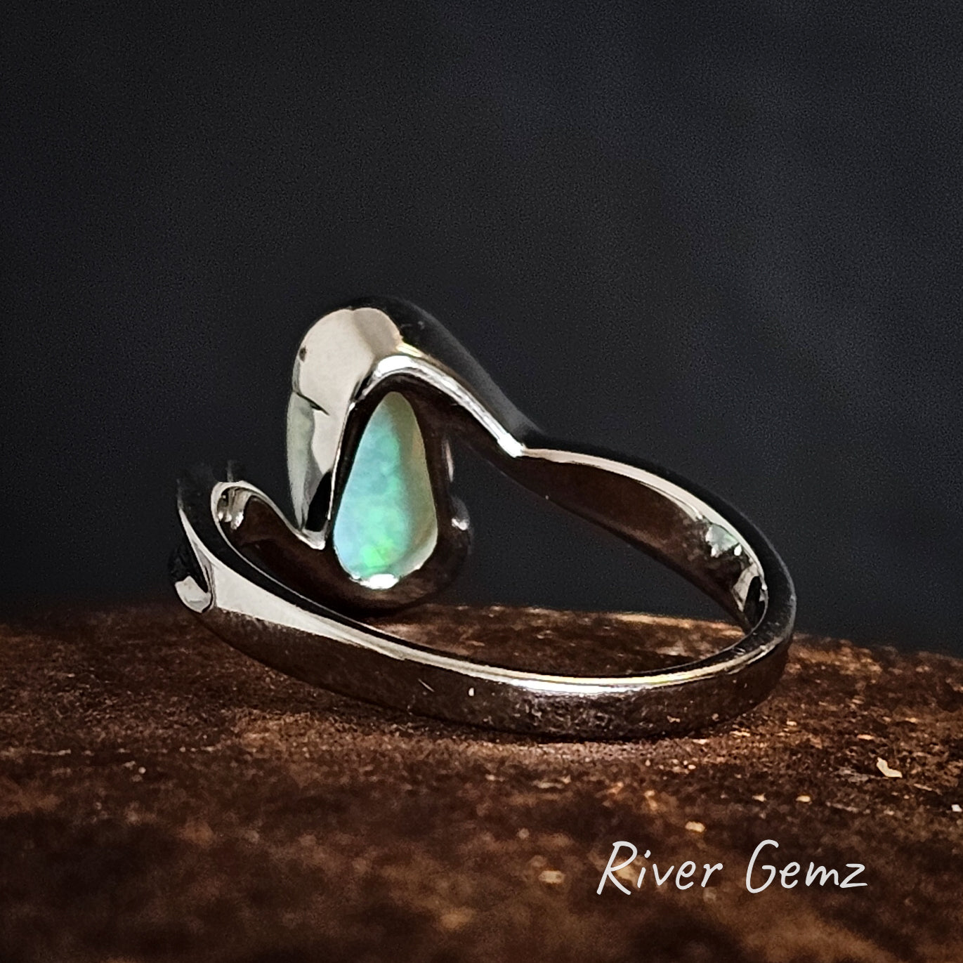 Back view of silver ring with a teardrop-shaped setting on a dark background, branded 'River Gemz'.