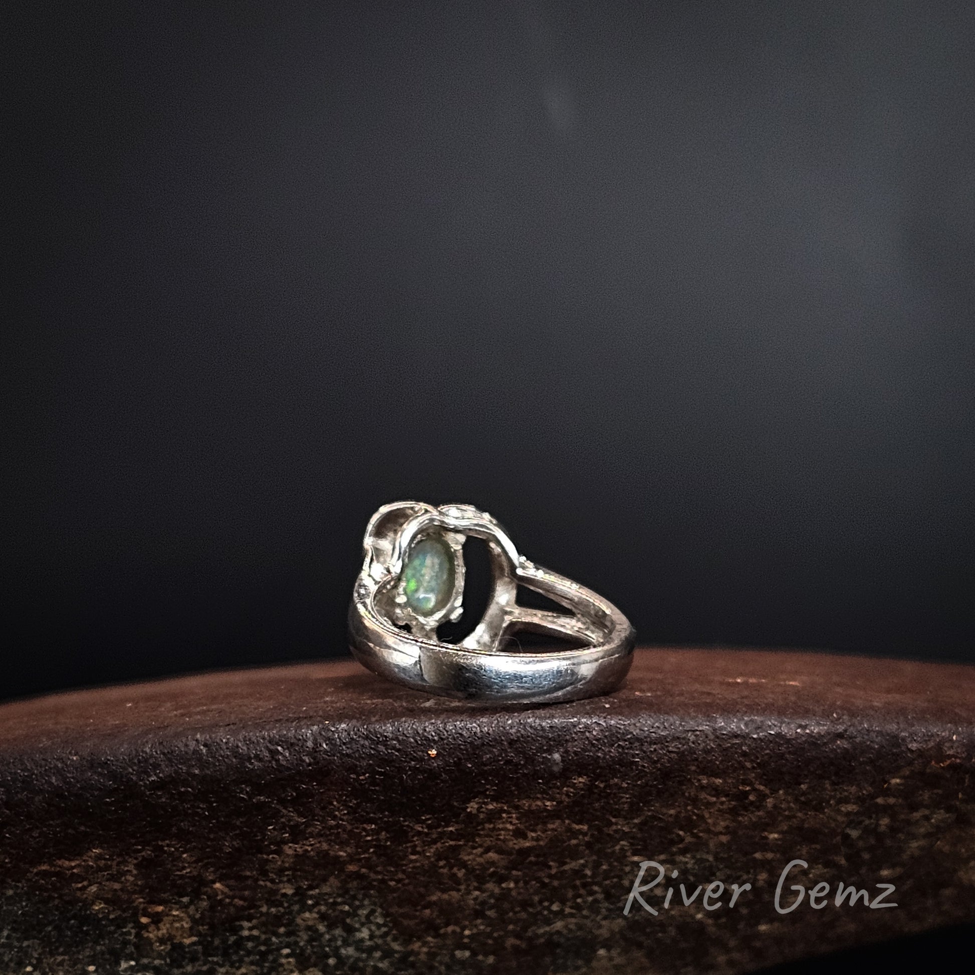 Rear view of silver ring showing the light base tone of the crystal opal in the ring. The brand name 'River Gemz' is visible as a watermark in the bottom right corner.