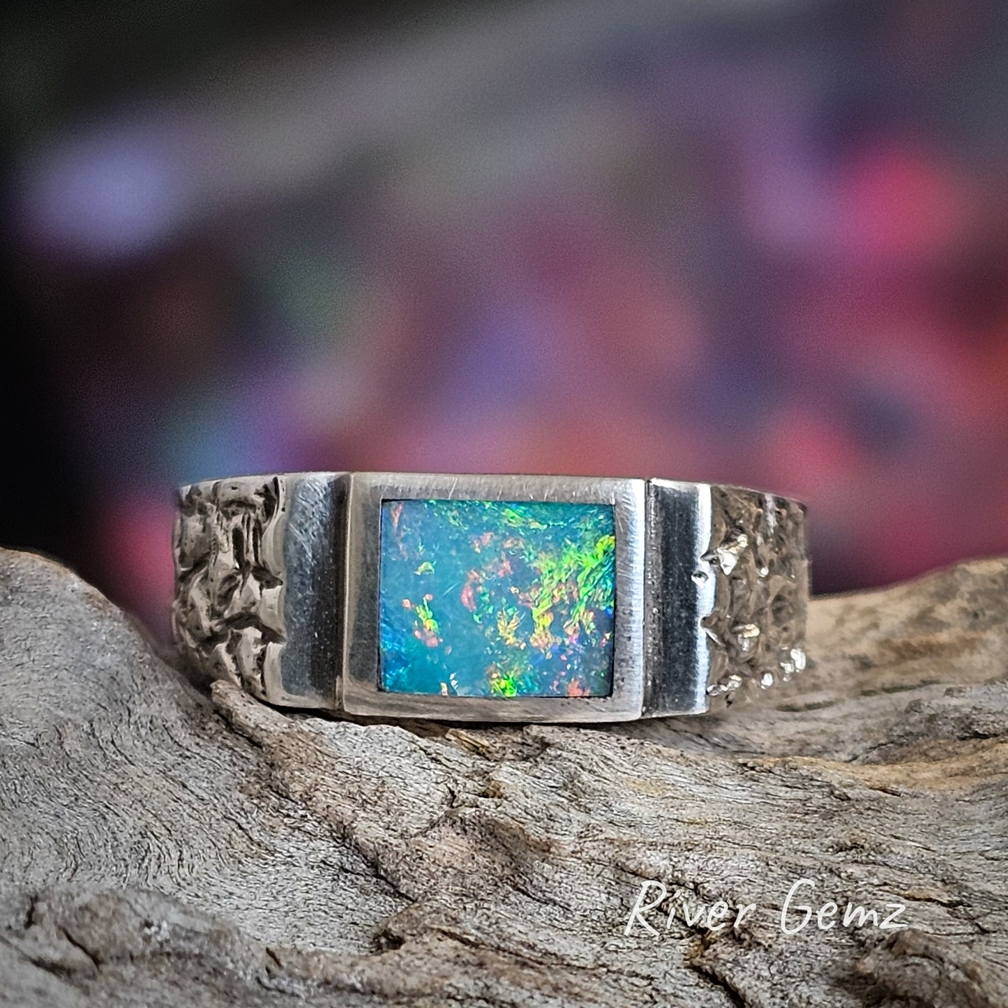 Multi-coloured rectangular shaped opal in silver ring.