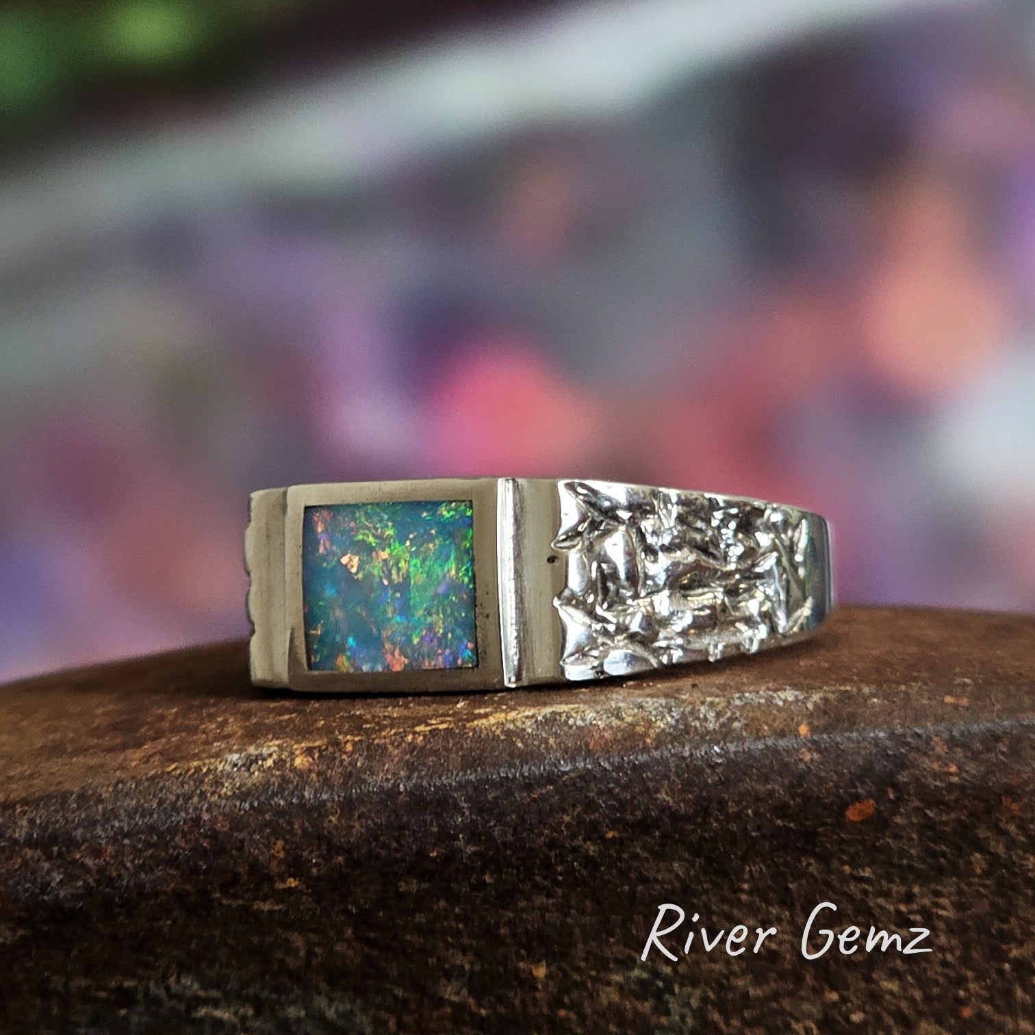 Colourful opal framed in sterling silver in men's ring.