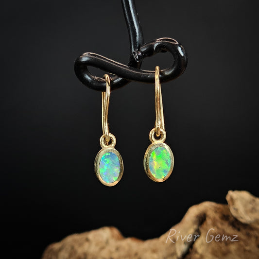 Oval shaped blue and green crystal opals besel set in yellow gold shepherd hook earrings.