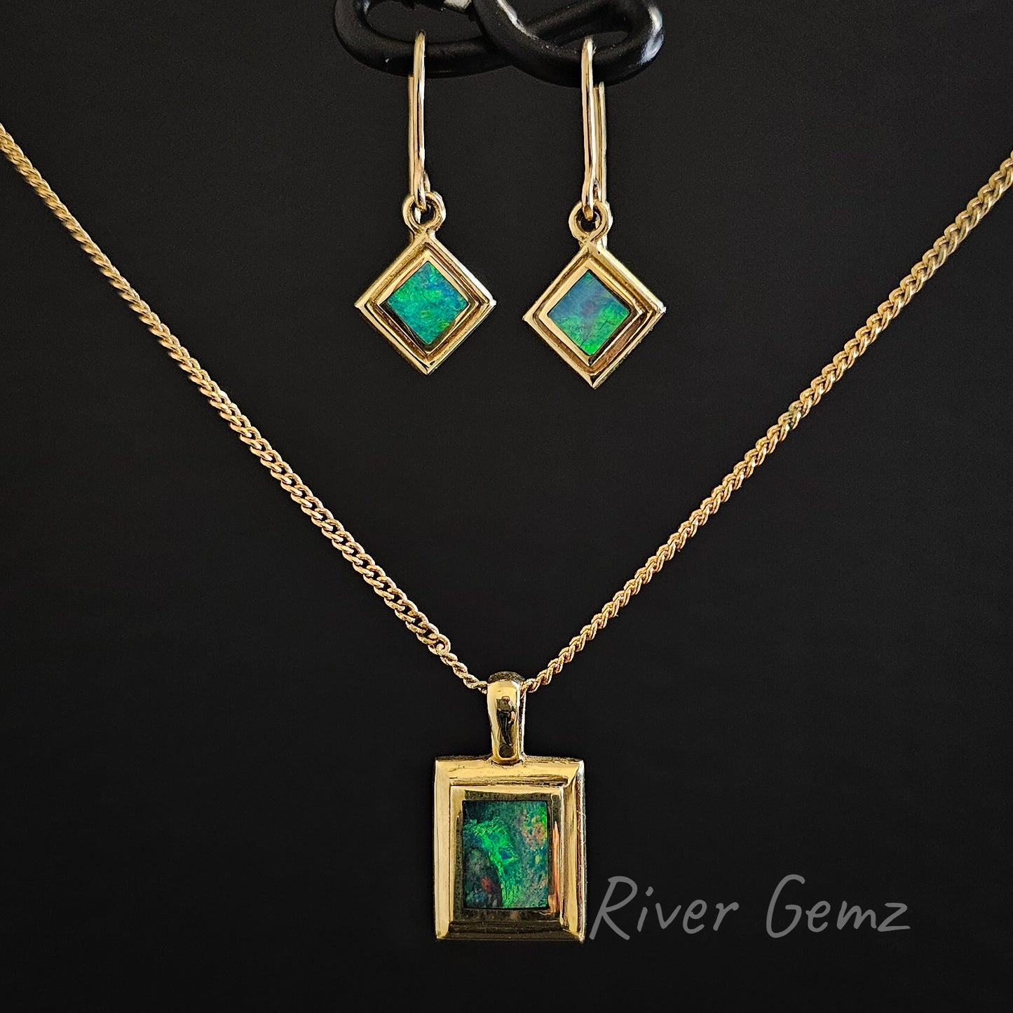 Hook earrings with matching pendant besel set in yellow gold against a black background.