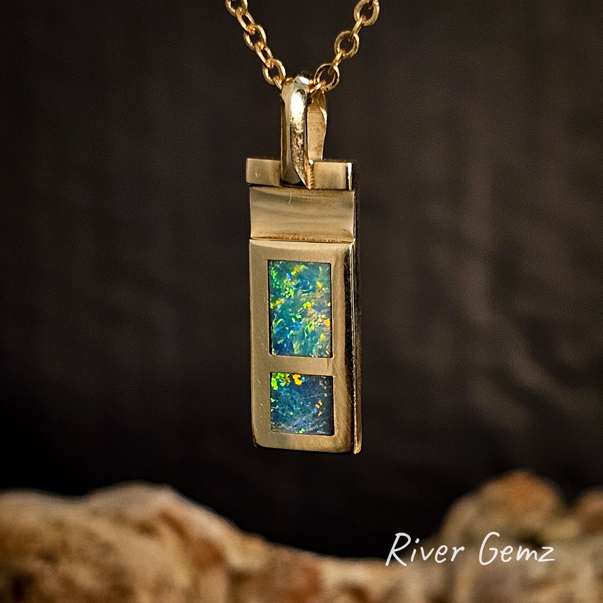 Gold pendant with two crystal opal stones on a dark background, featuring 'River Gemz' branding.