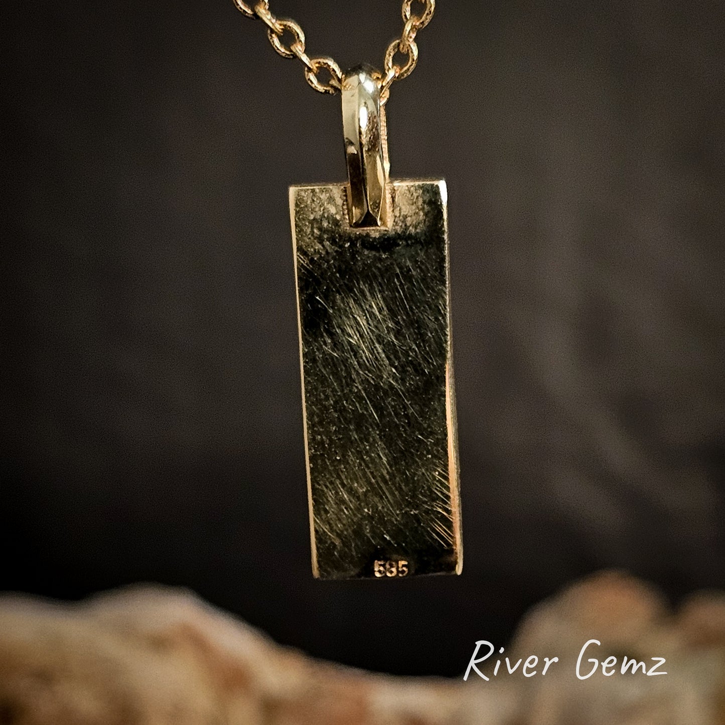 Back of gold pendant showing the 595 stamp to indicate 14K gold on a dark background, featuring the brand 'River Gemz'.