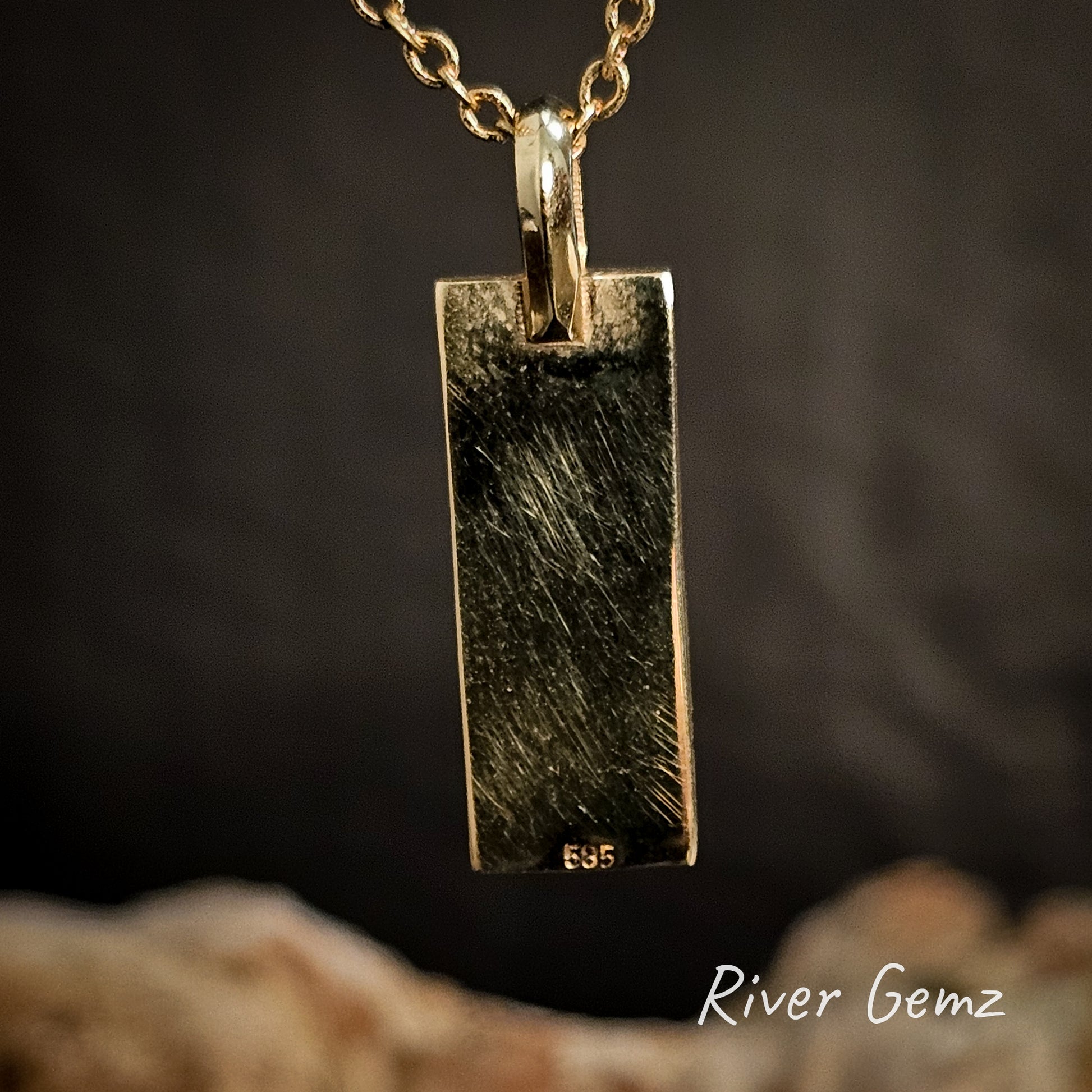 Back of gold pendant showing the 595 stamp to indicate 14K gold on a dark background, featuring the brand 'River Gemz'.