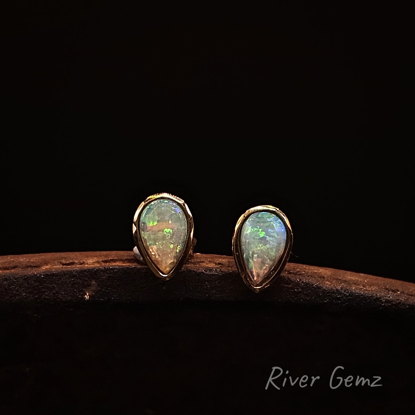 Teardrop shaped light opal earrings on a dark background with 'River Gemz' branding.