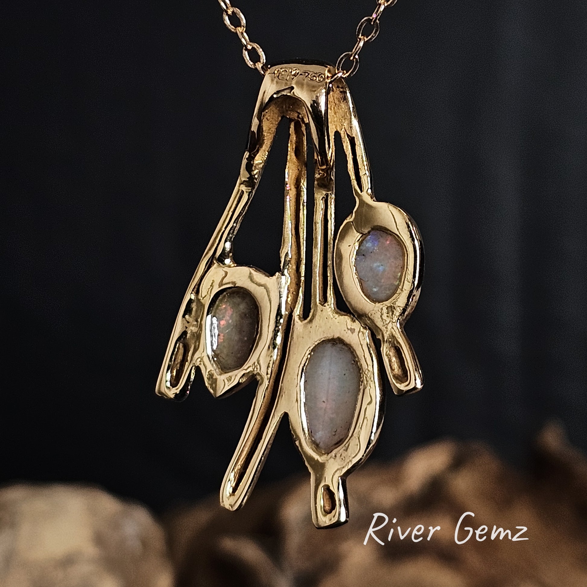 Back of gold pendant to show the light base tone of the three crystal opals on a dark background, featuring 'River Gemz' branding.