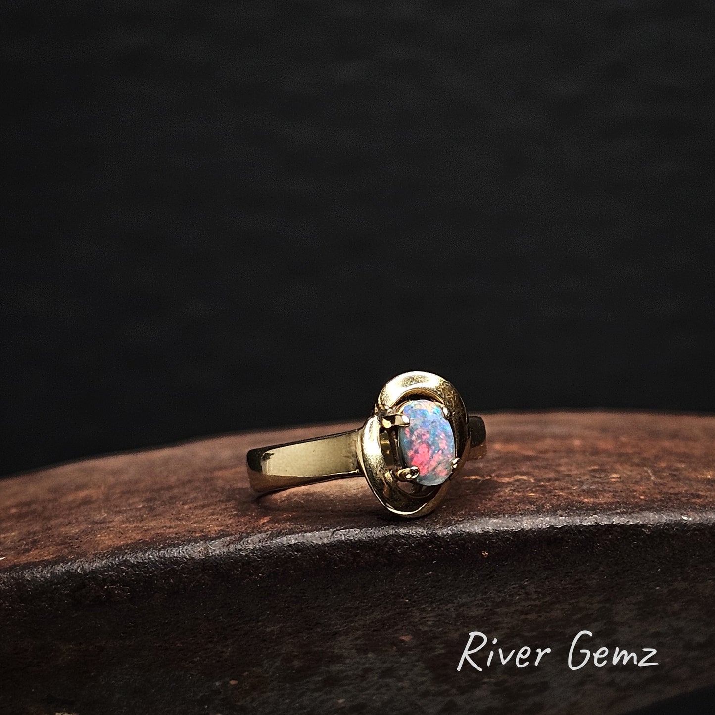 Vivid red on blue in the oval shaped opal set in yellow gold ring.