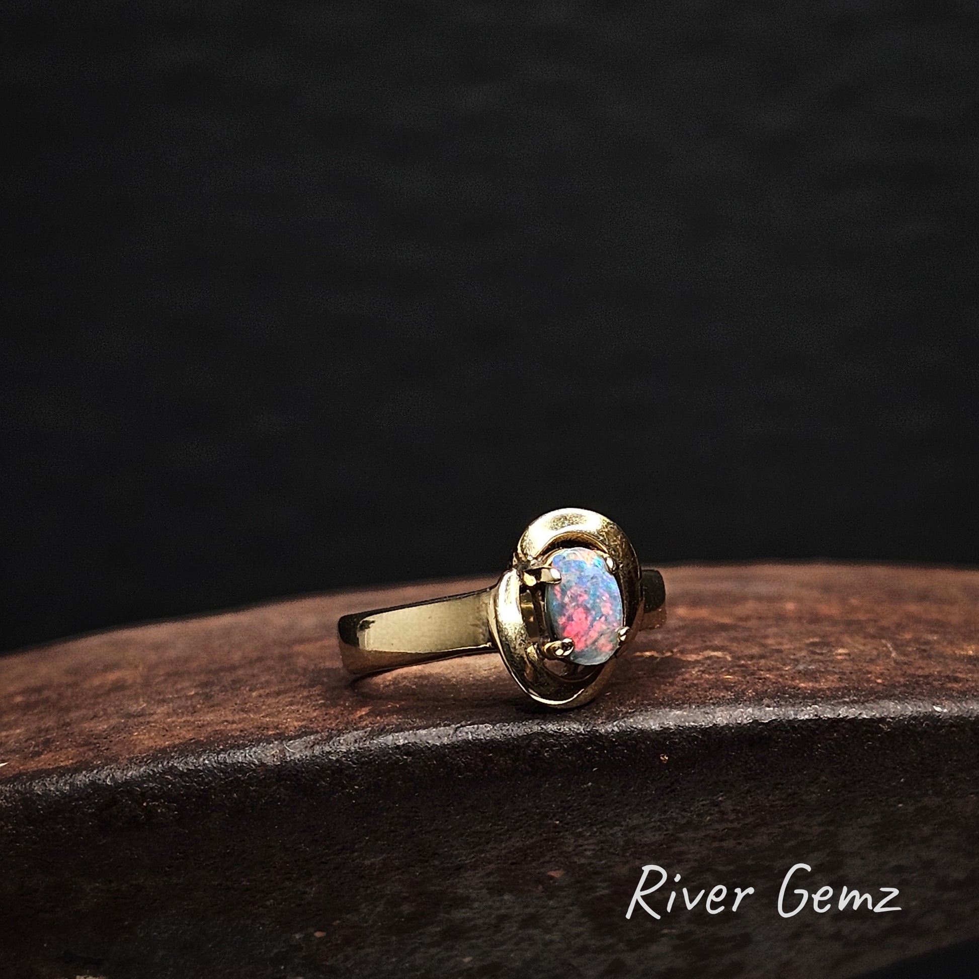 Vivid red on blue in the oval shaped opal set in yellow gold ring.