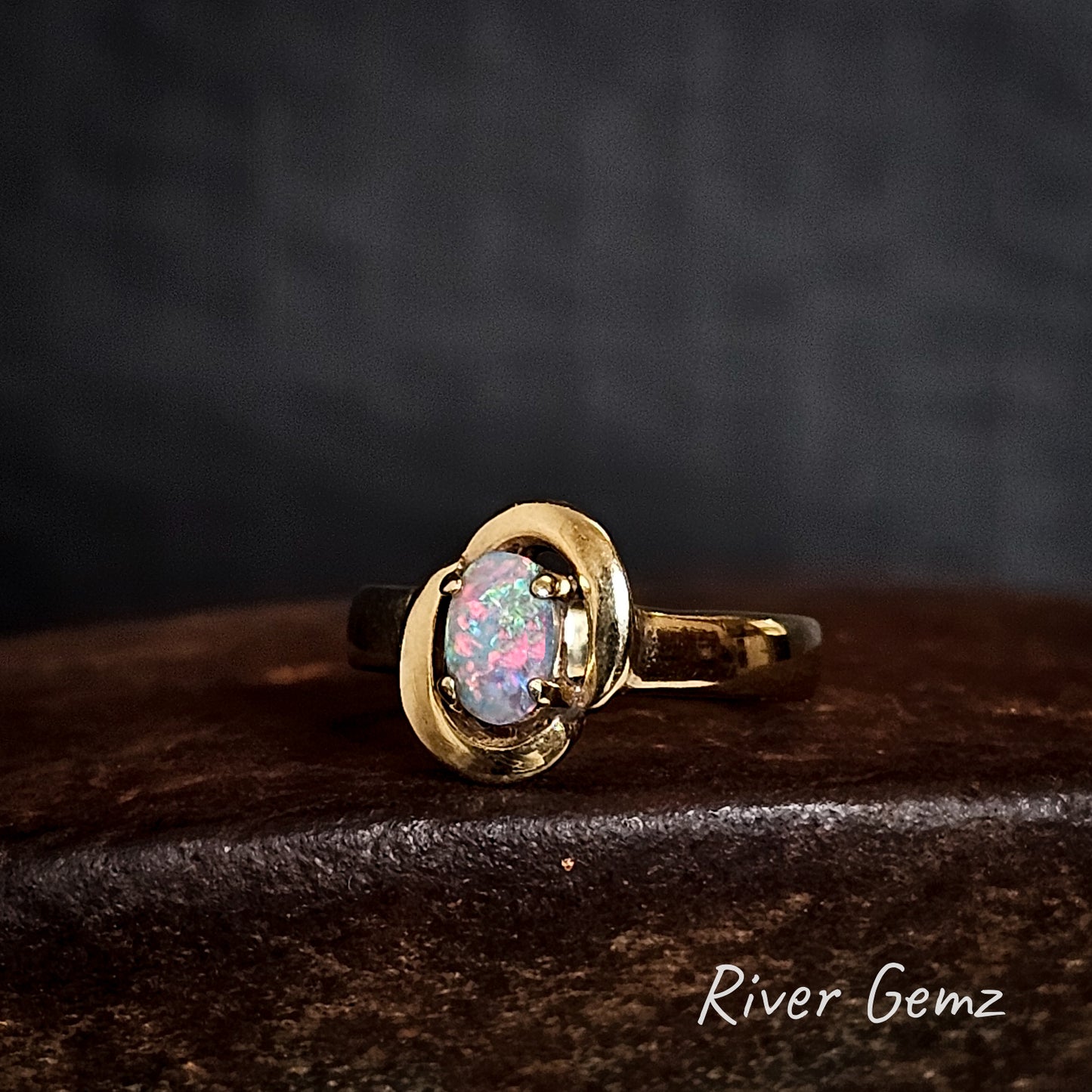 Multi-coloured oval shaped opal claw set in yellow gold ring.