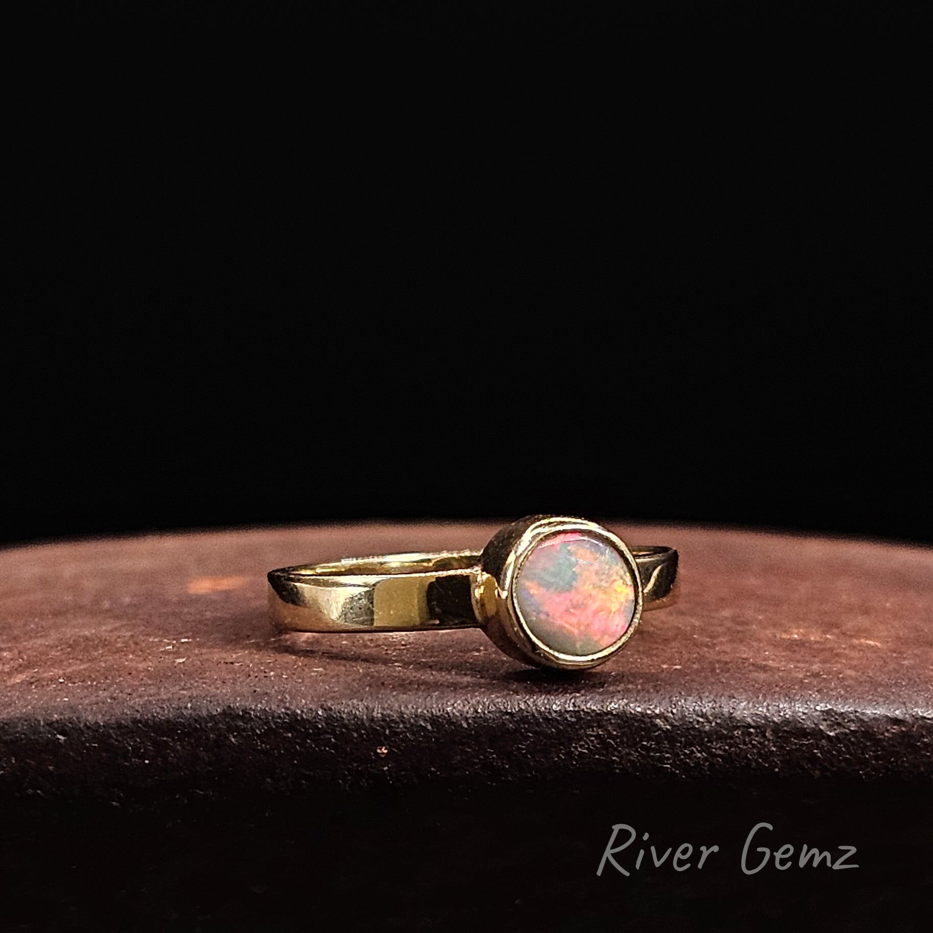 Dark opal set in yellow gold ring with straight shank.