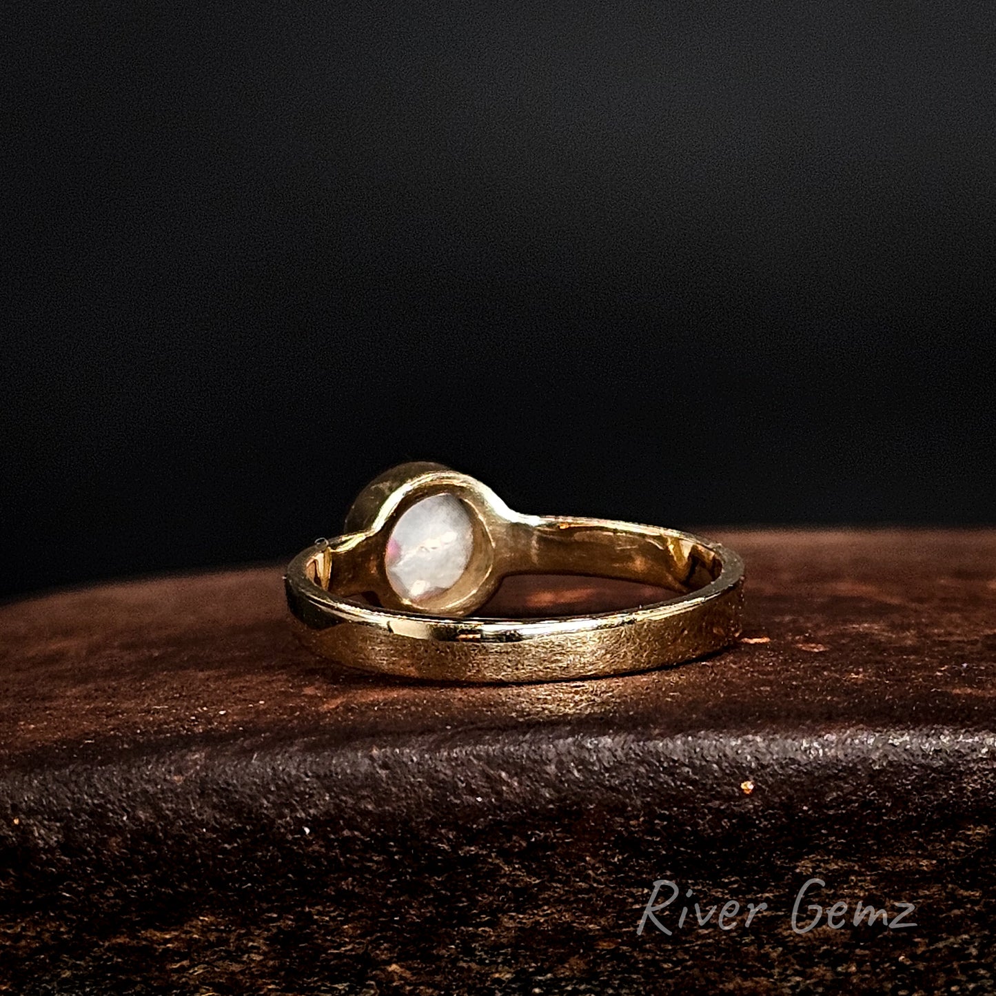 Rear view of the yellow gold ring shows the grey base tone of the semi-black opal set in it.