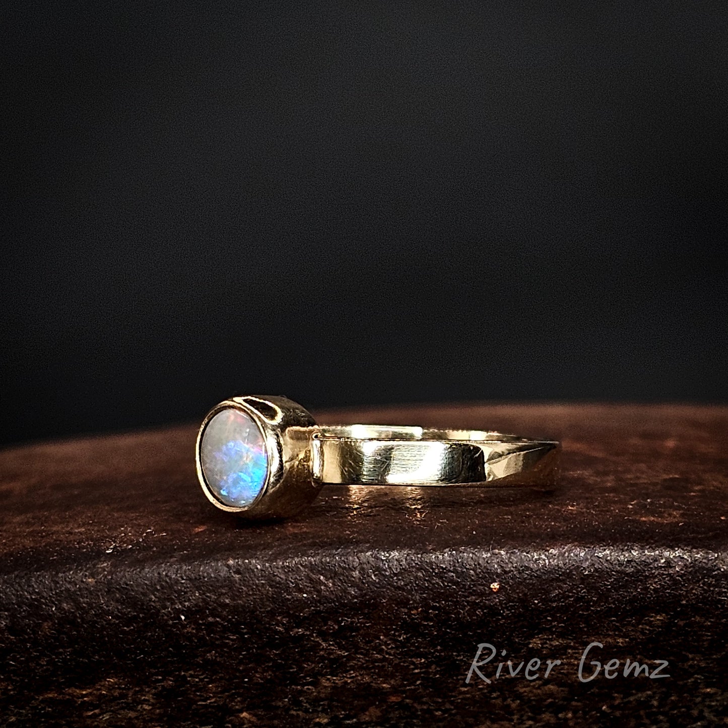 Multi-coloured circular opal set in yellow gold ring.