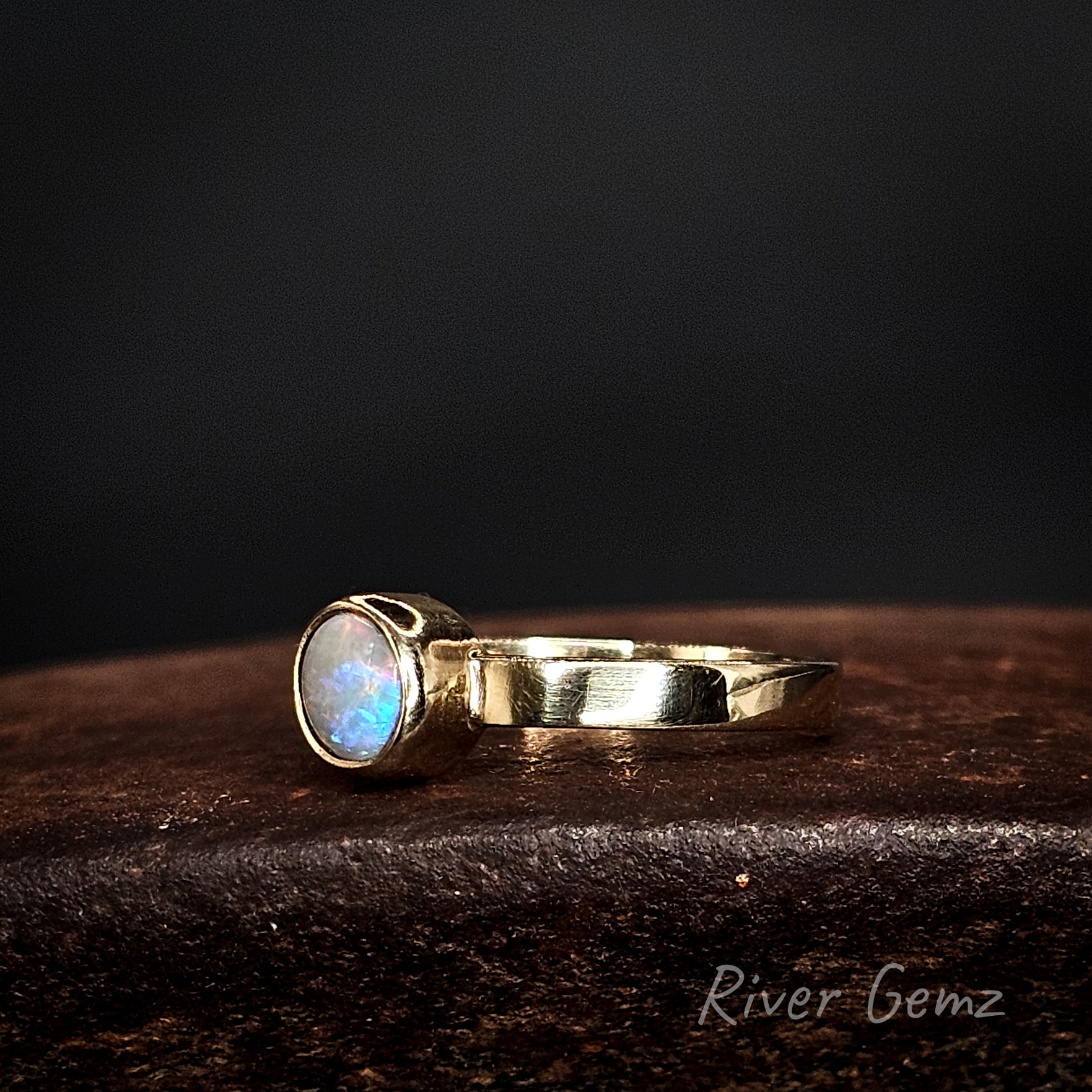 Multi-coloured circular opal set in yellow gold ring.