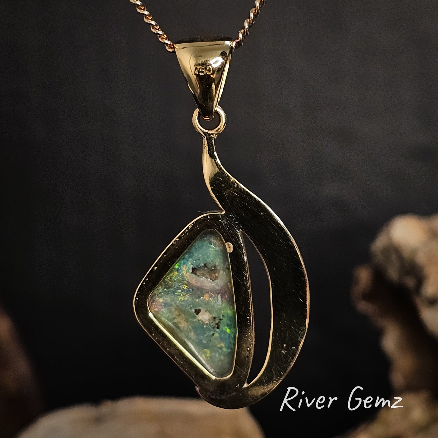 Rear of the gold pendant showing the grey tone of the semi-black opal on a dark background, featuring 'River Gemz' branding.
