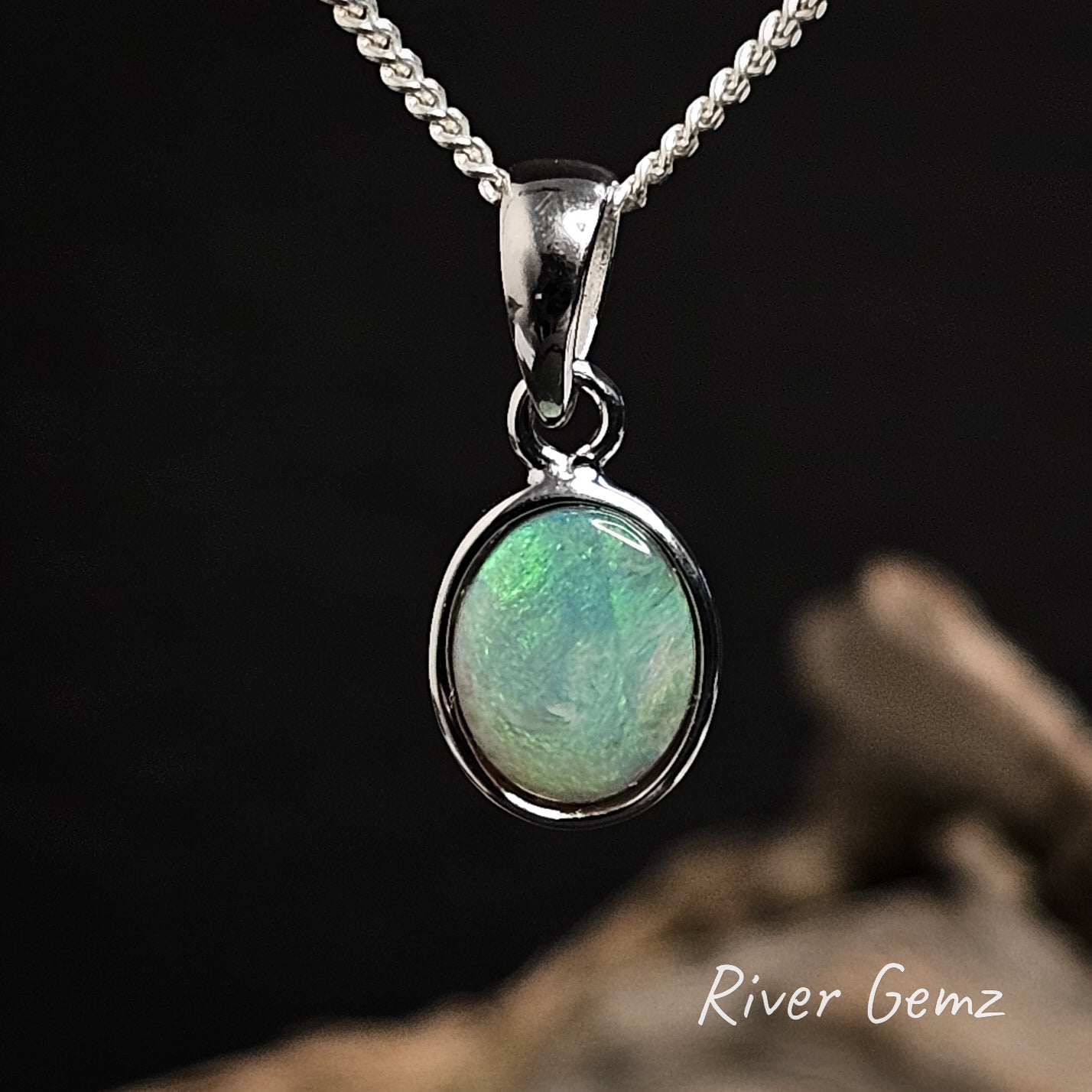 Oval shaped orange and green opal pendant silver necklace on a dark background with 'River Gemz' branding.
