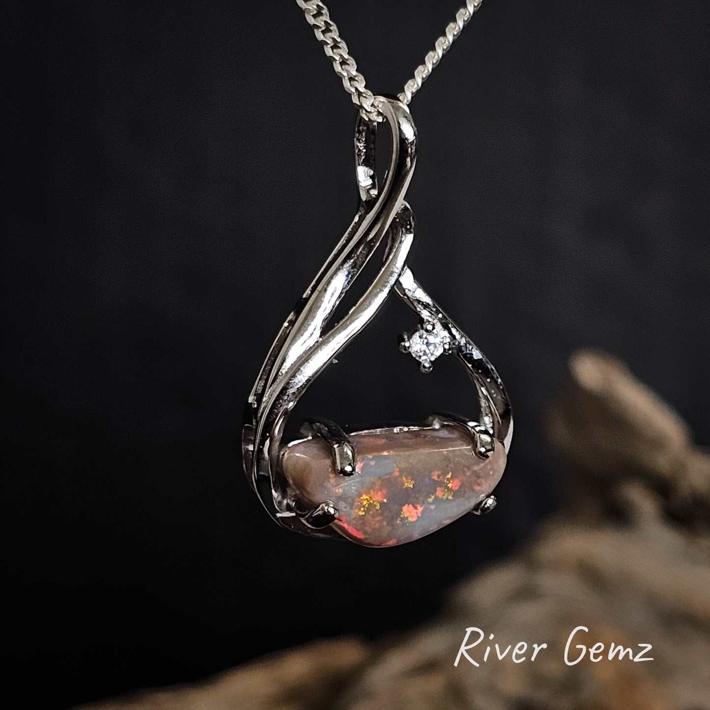 Dark opal with red, orange and yellow colours set in sterling silver pendant.
