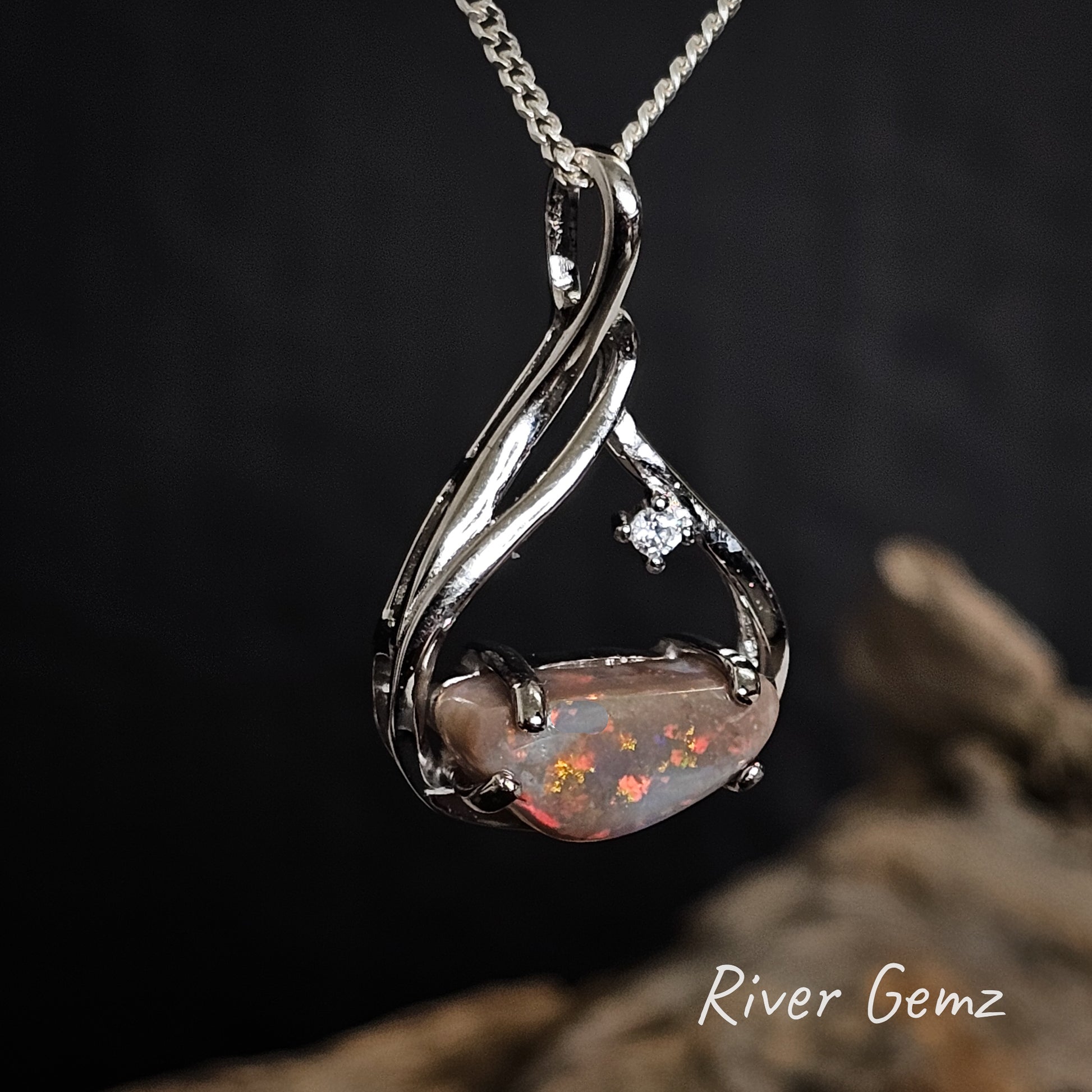 Dark opal with red, orange and yellow colours set in sterling silver pendant.