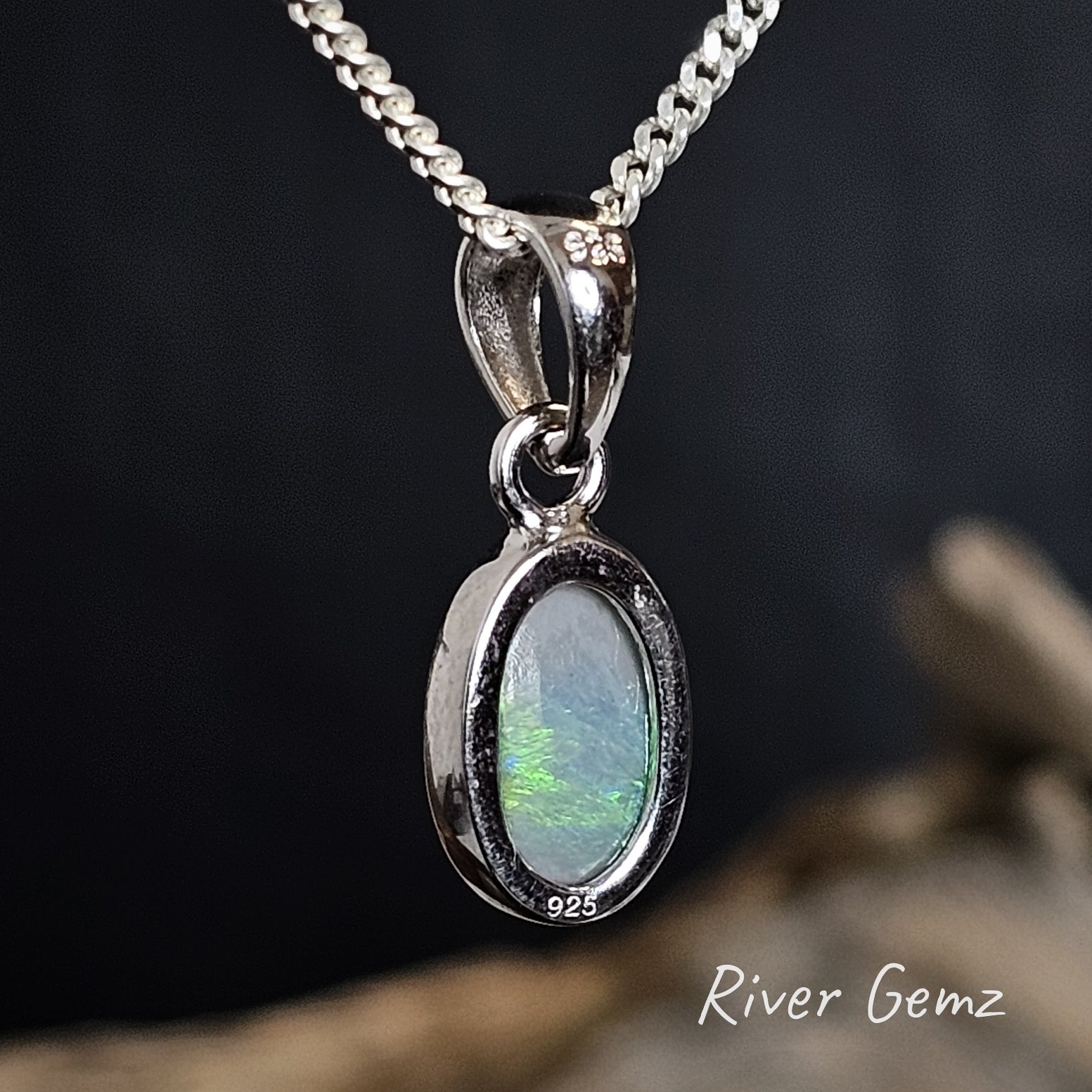 Back of pendant showing 925 stamp for sterling silver and the dark tone of the semi-black opal on a dark background, featuring 'River Gemz' branding.