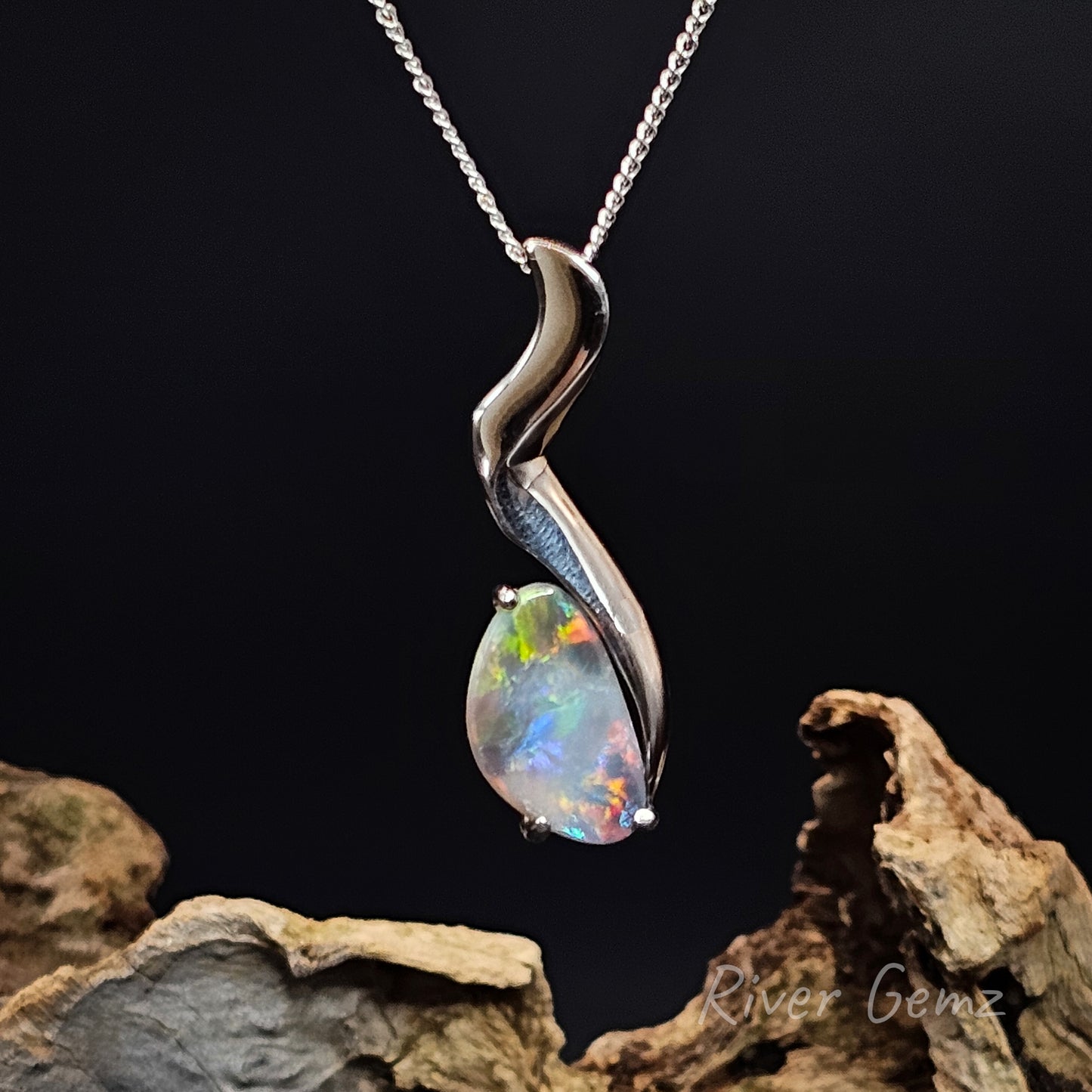 Opal pendant on a silver chain against a dark background