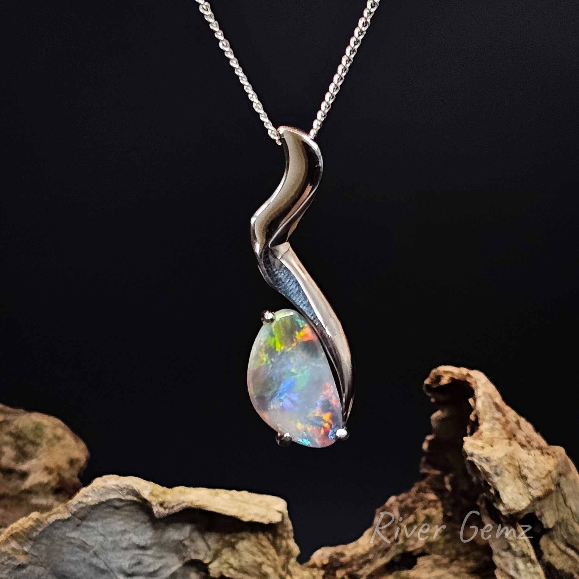 Opal pendant on a silver chain against a dark background
