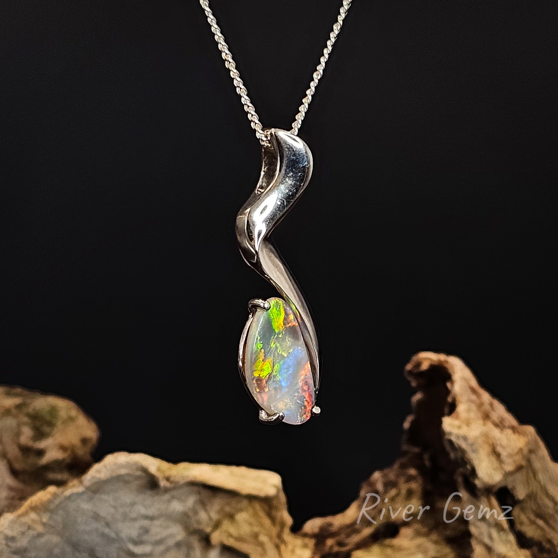 Silver pendant with a colorful gemstone on a dark background