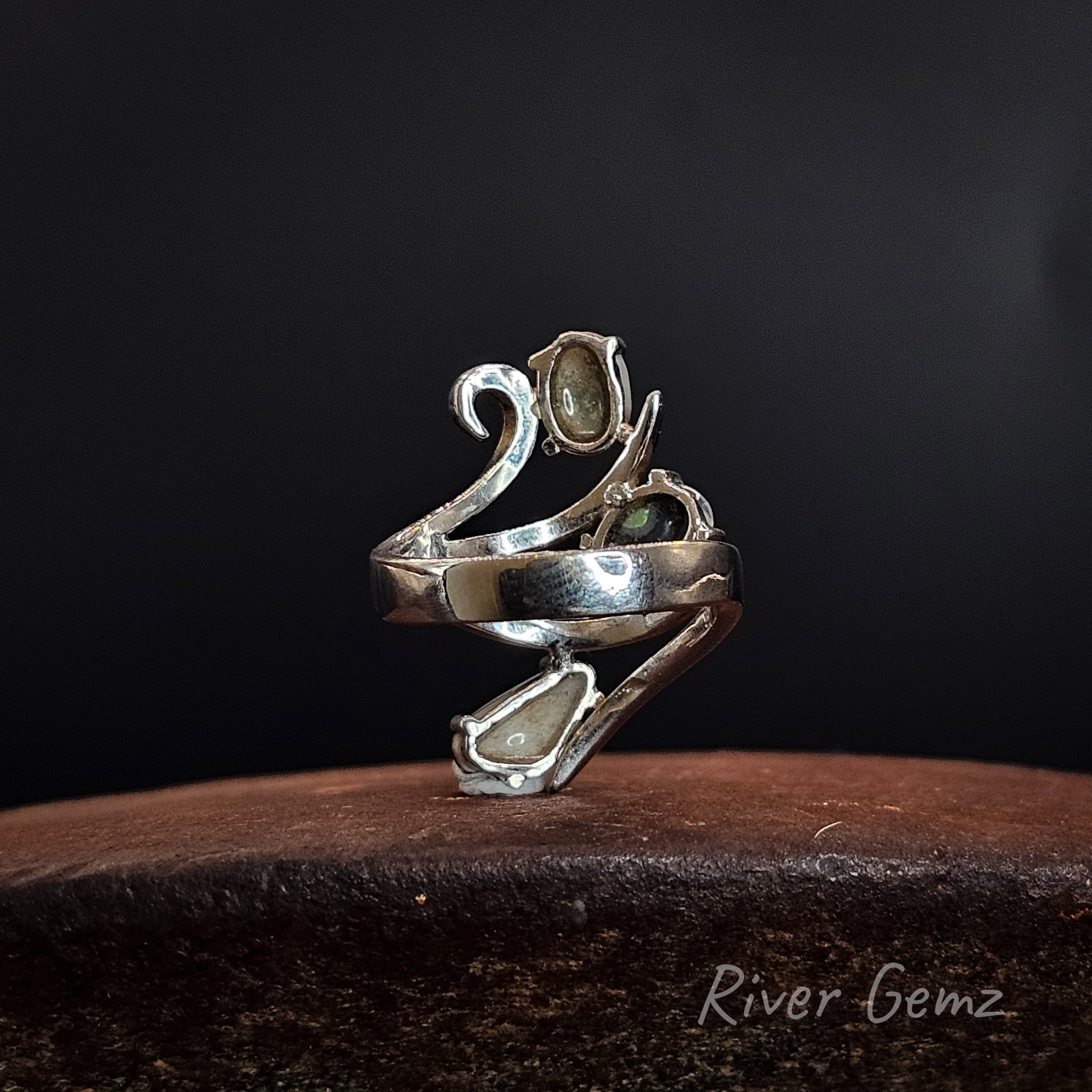 Rear view shows the dark base tone of the 3 semi-black opals set in the silver ring. The brand name 'River Gemz' is visible as a watermark in the bottom right corner.