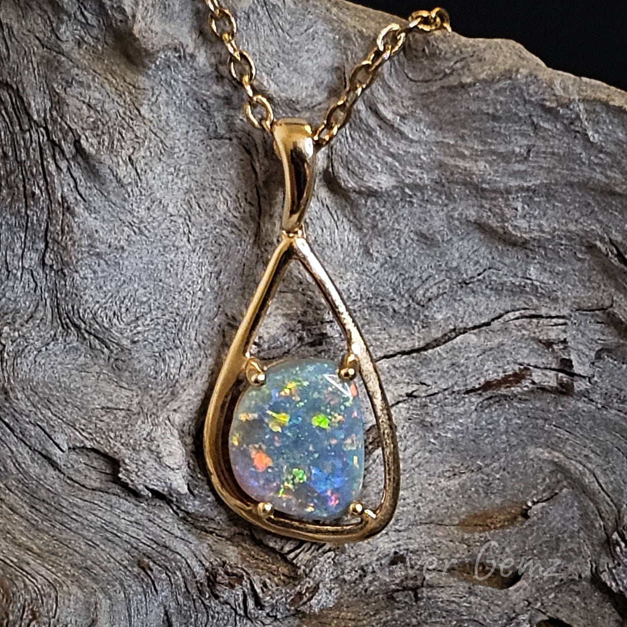 Multi-coloured semi-black opal in a tear drop shaped gold necklace.