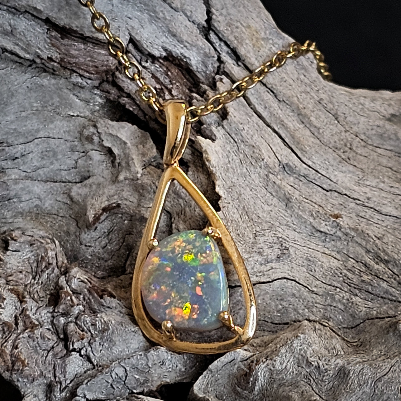 Modern design gold pendant with gem quality semi-black opal.