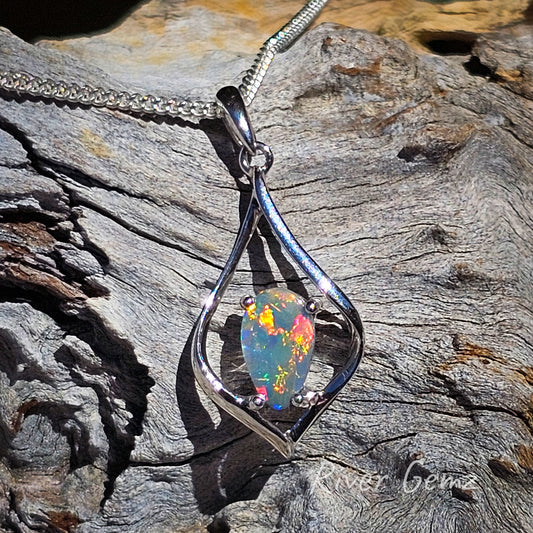 Multi-coloured dark opal claw set in diamond shaped silver pendant.