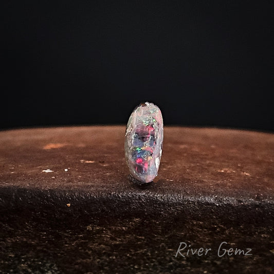 Opal gemstone on a dark surface with 'River Gemz' branding.