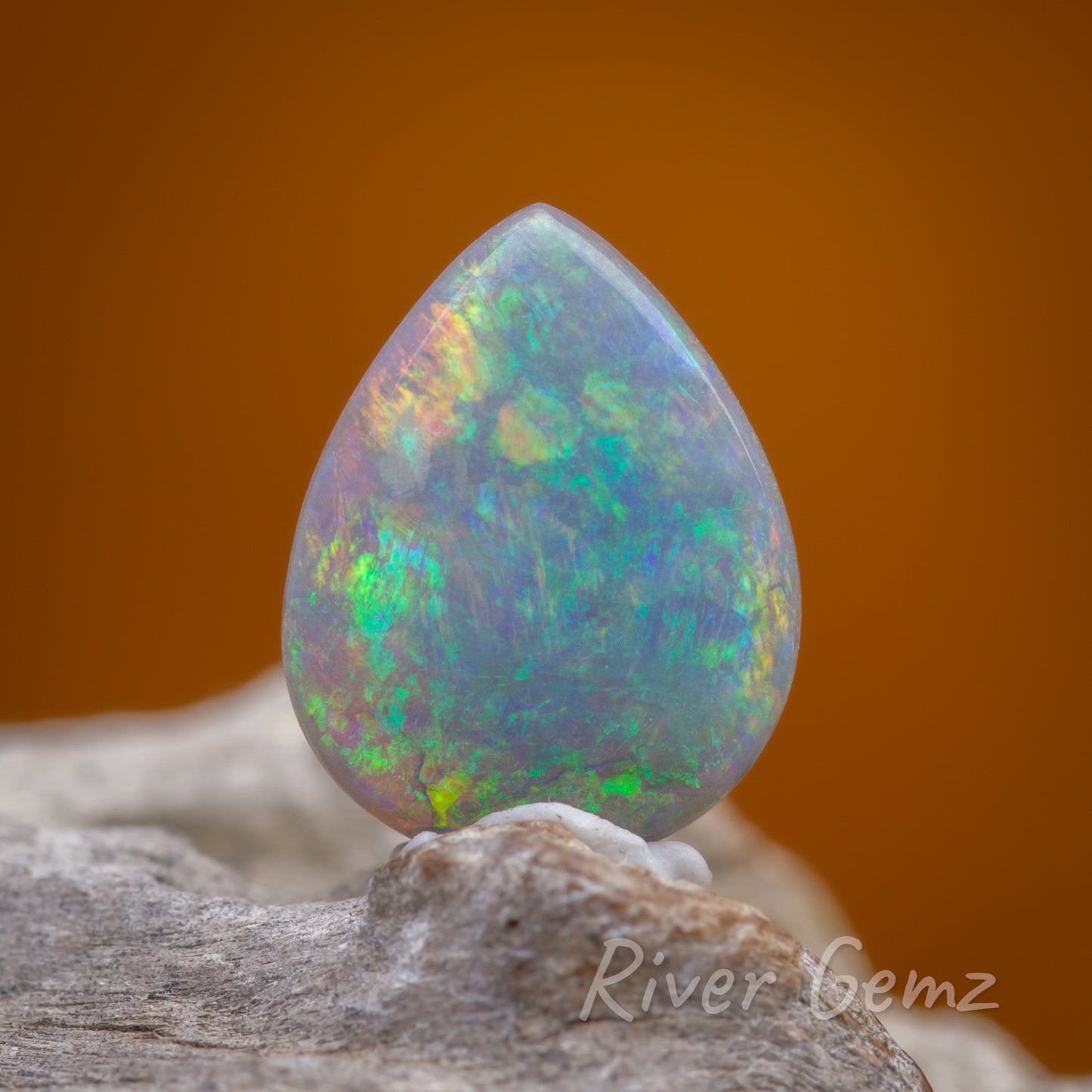 Front view of colourful tear drop shaped opal standing upright.