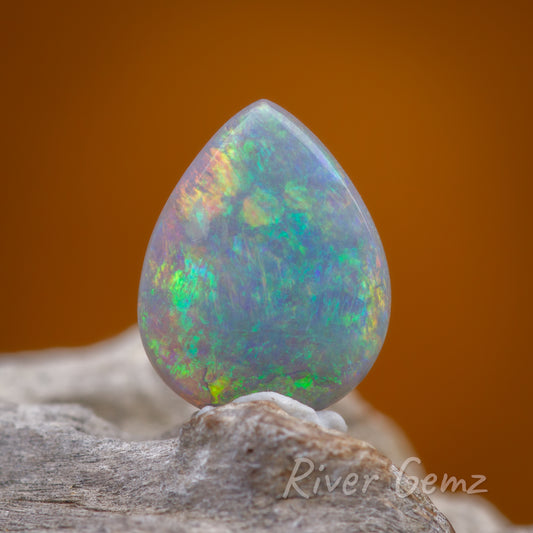 Front view of colourful tear drop shaped opal standing upright.