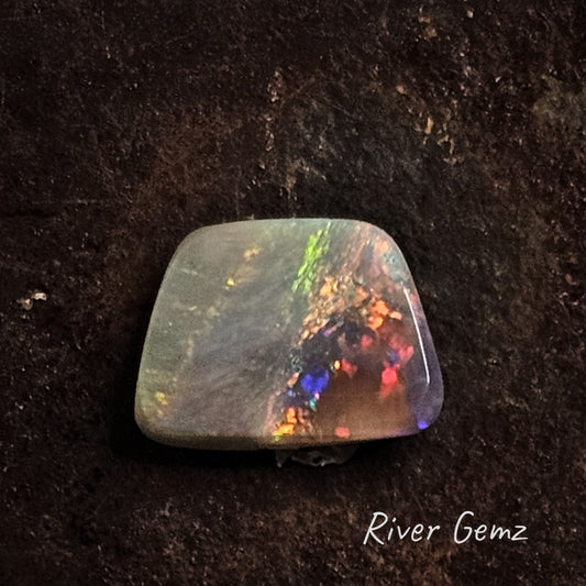 Multi-coloured dark opal cut in a trapezium shape.