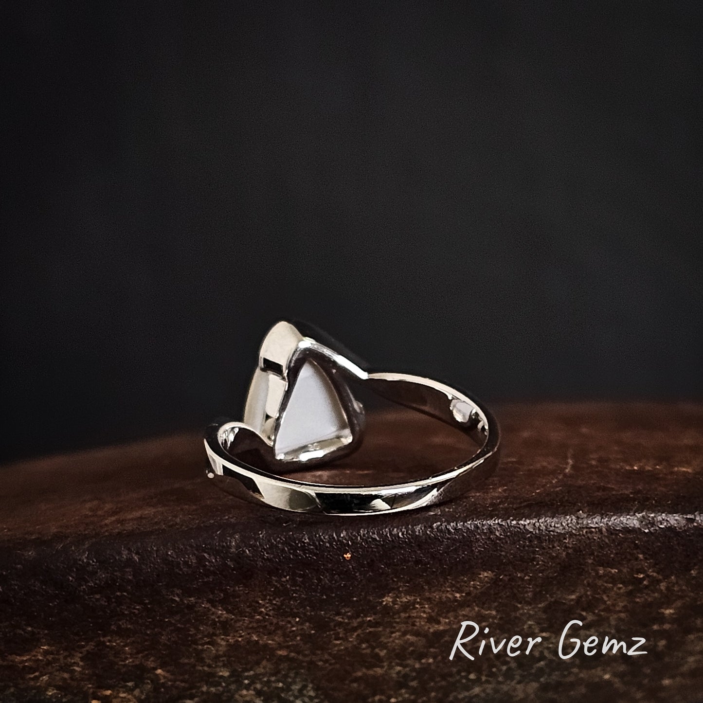 Back of silver ring showing the light tone base of the white opal on a dark surface, branded 'River Gemz'.