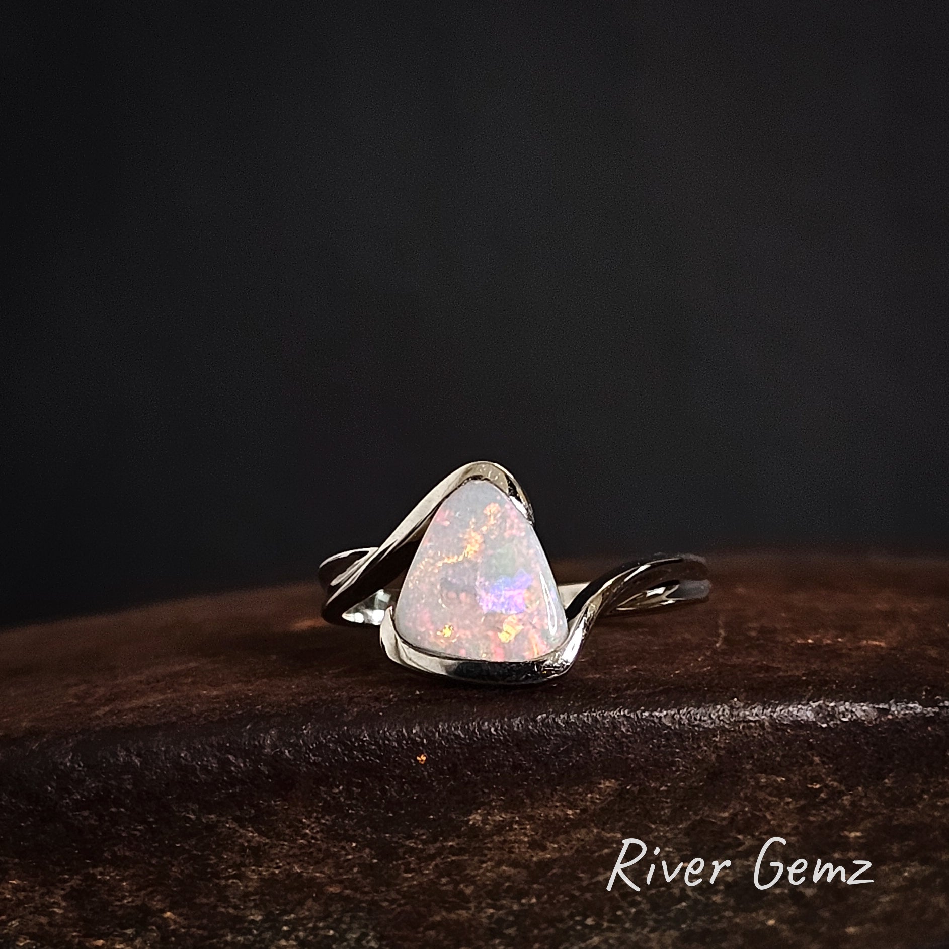 Opal ring with silver setting on a dark background, featuring the brand 'River Gemz'.