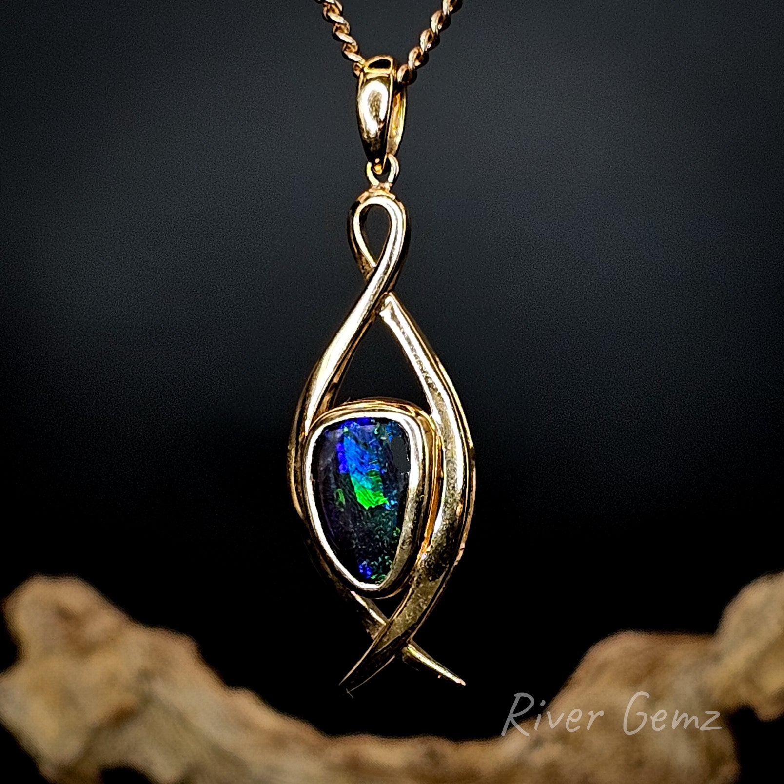 Gold pendant with a colorful gemstone on a dark background