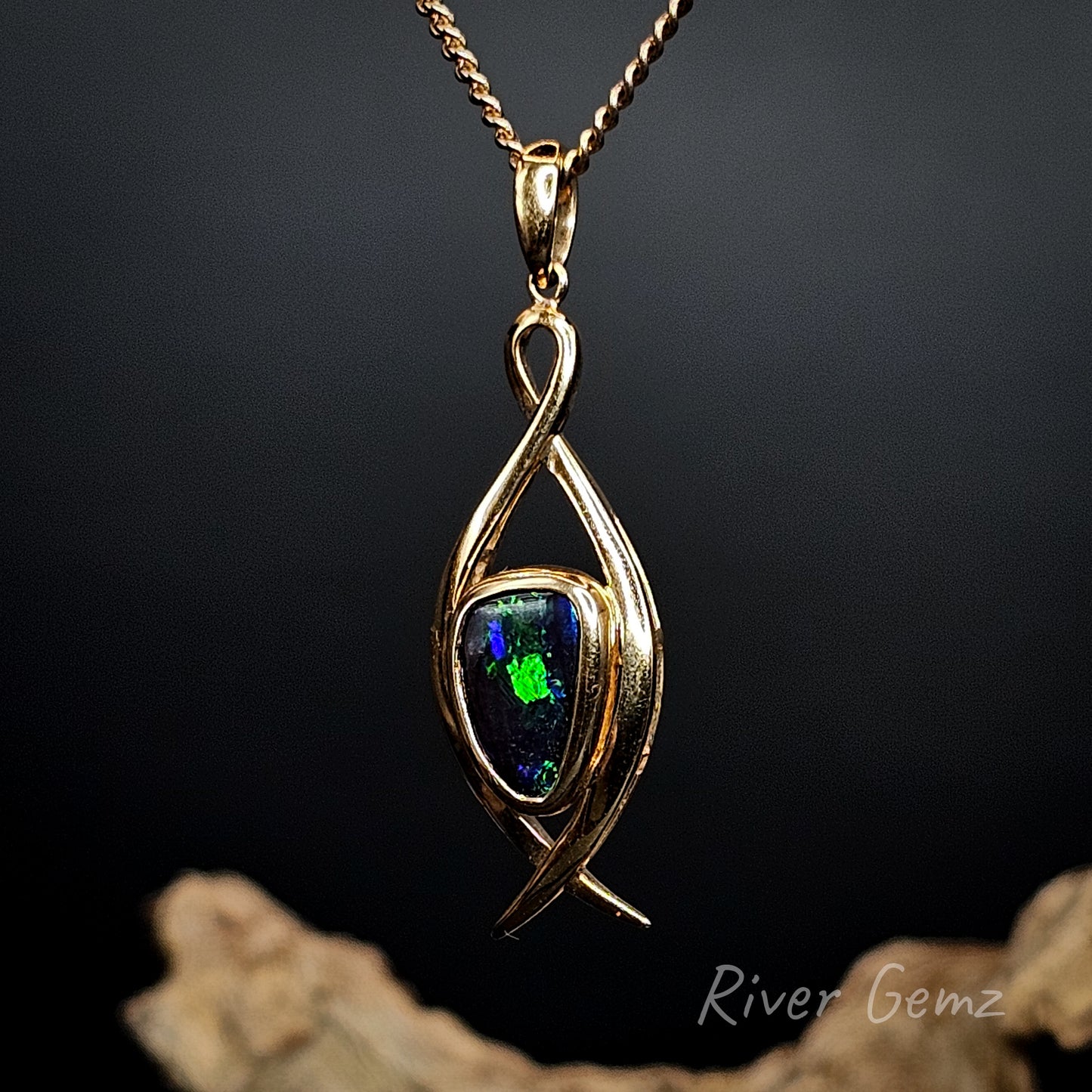 Gold pendant with a blue and green dark opal on a dark background, featuring 'River Gemz' branding.